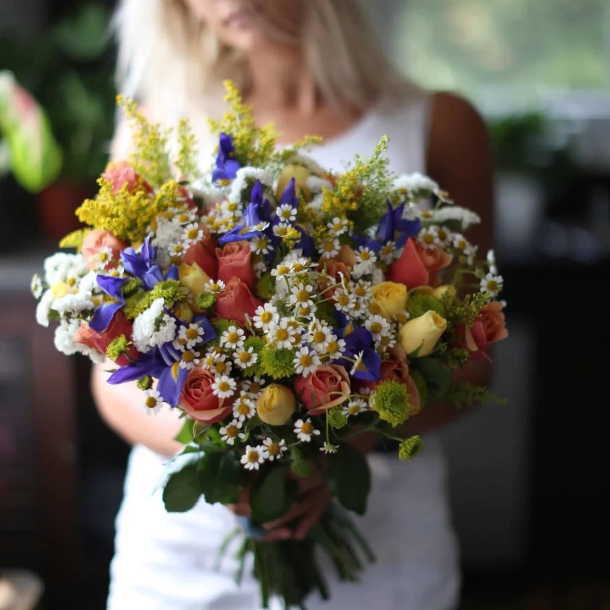 Woman holding a colorful bouquet of roses and daisies