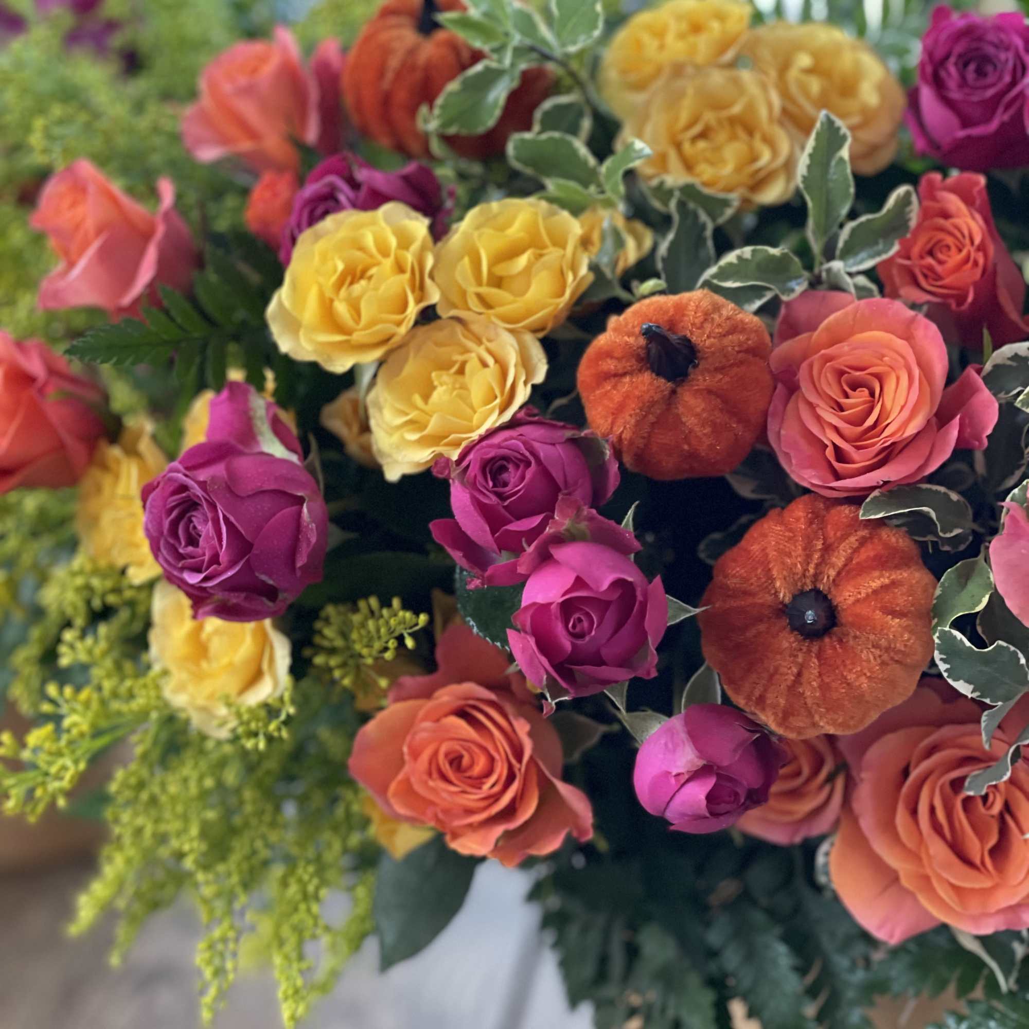 Bouquet of multicolored roses with orange pumpkin accents