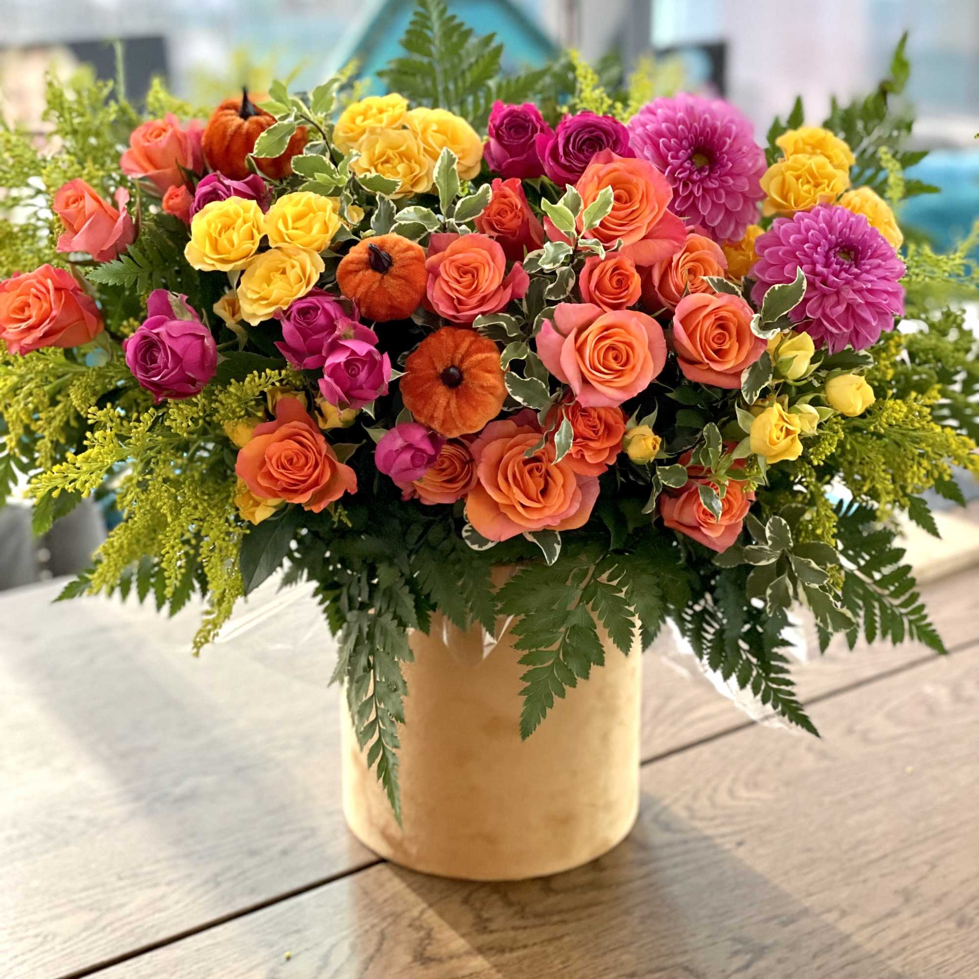 Bright mixed bouquet of roses and dahlias in a gold vase