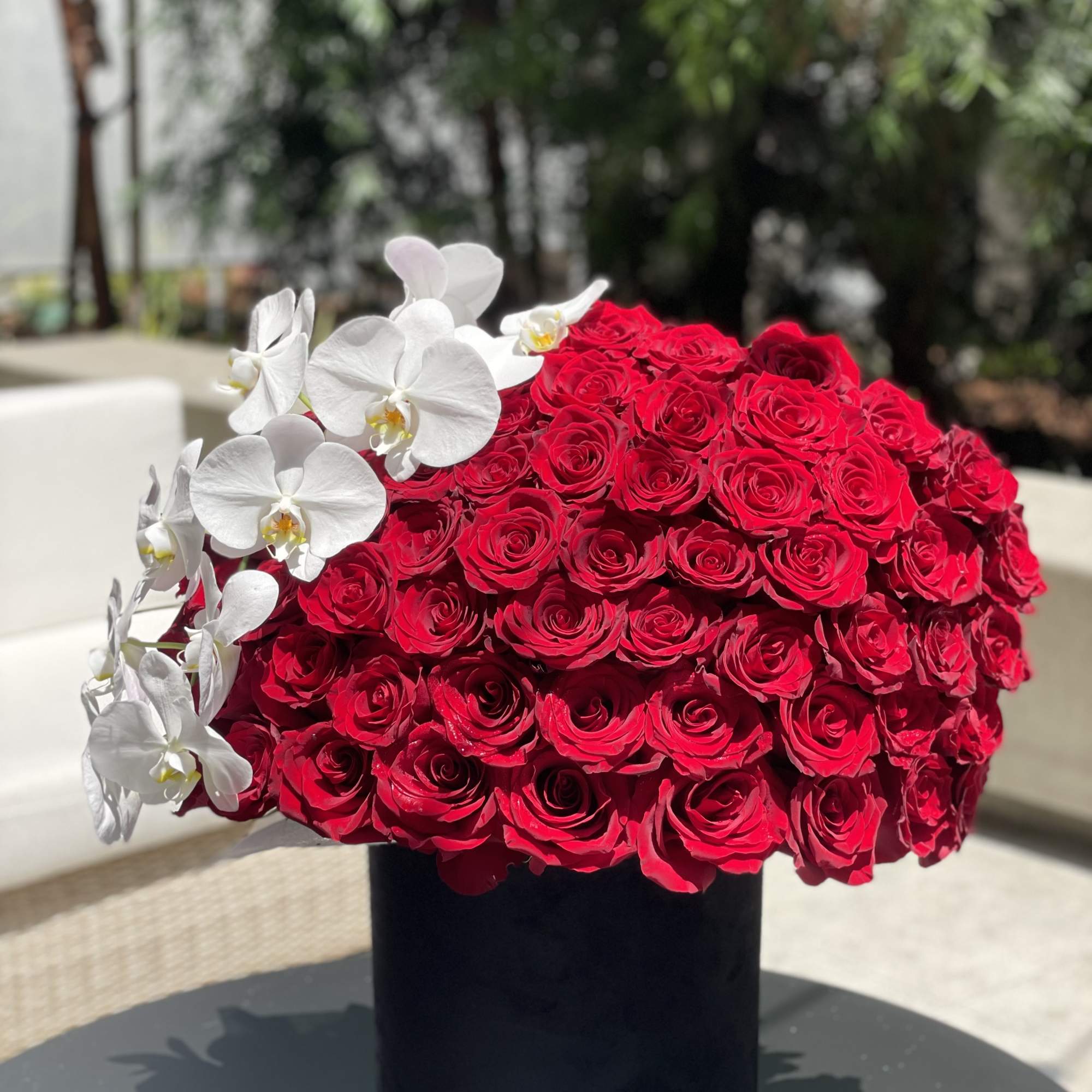 Red rose arrangement with white orchids in a black vase, photo 2 of 4