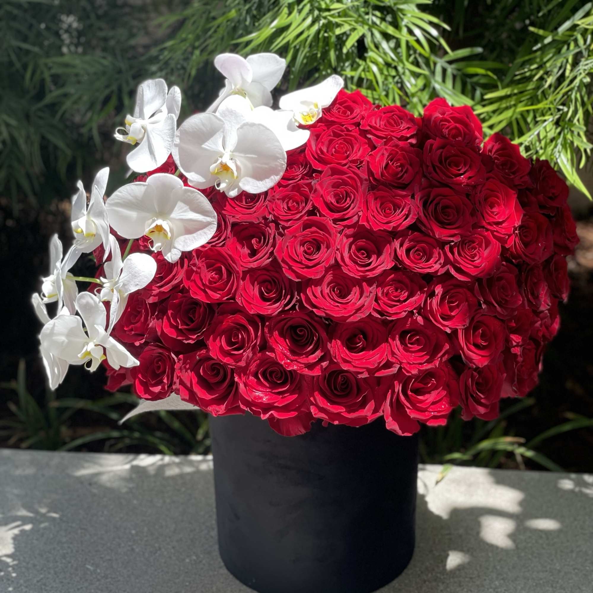 Red rose arrangement with white orchids in a black vase, photo 3 of 4