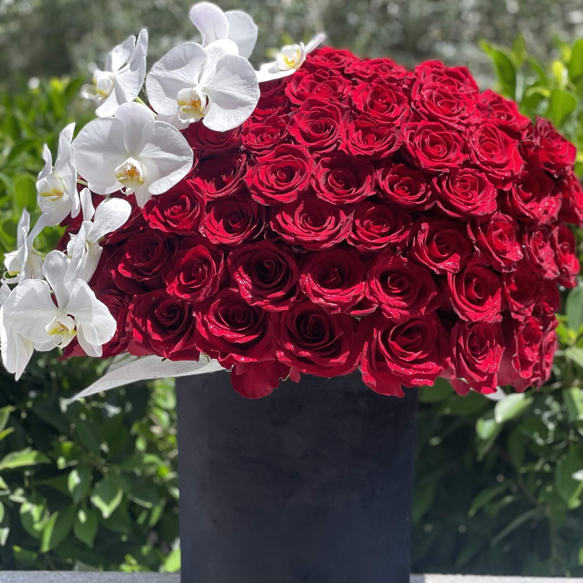 Red rose arrangement with white orchids in a black vase, photo 4 of 4