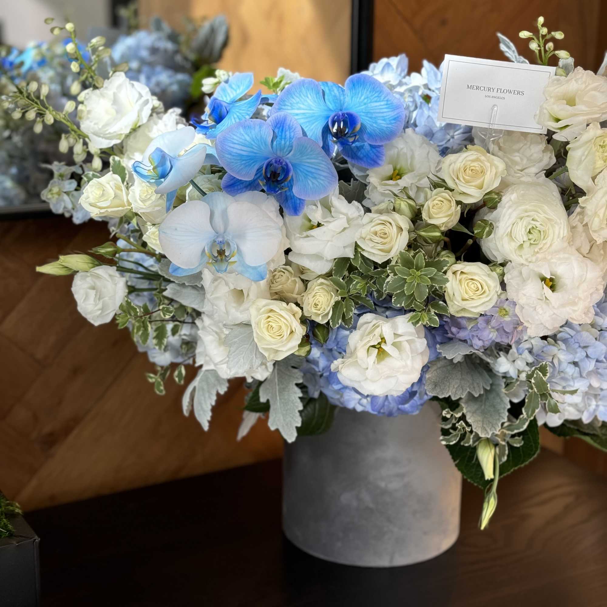 Blue orchids and white roses arranged in a gray vase