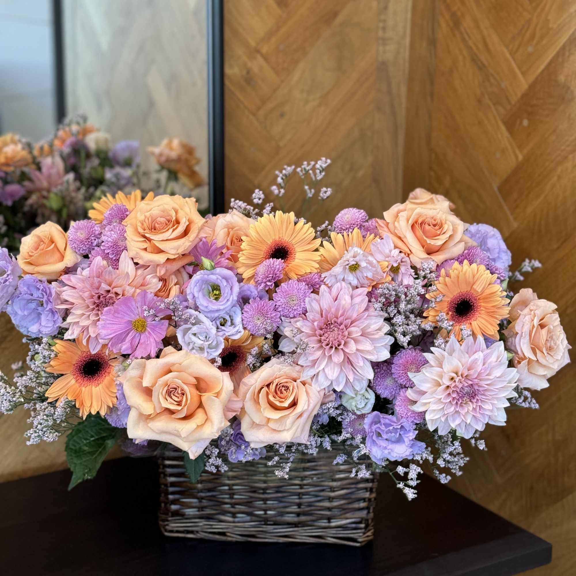 Peach roses and lavender flowers in a wicker basket