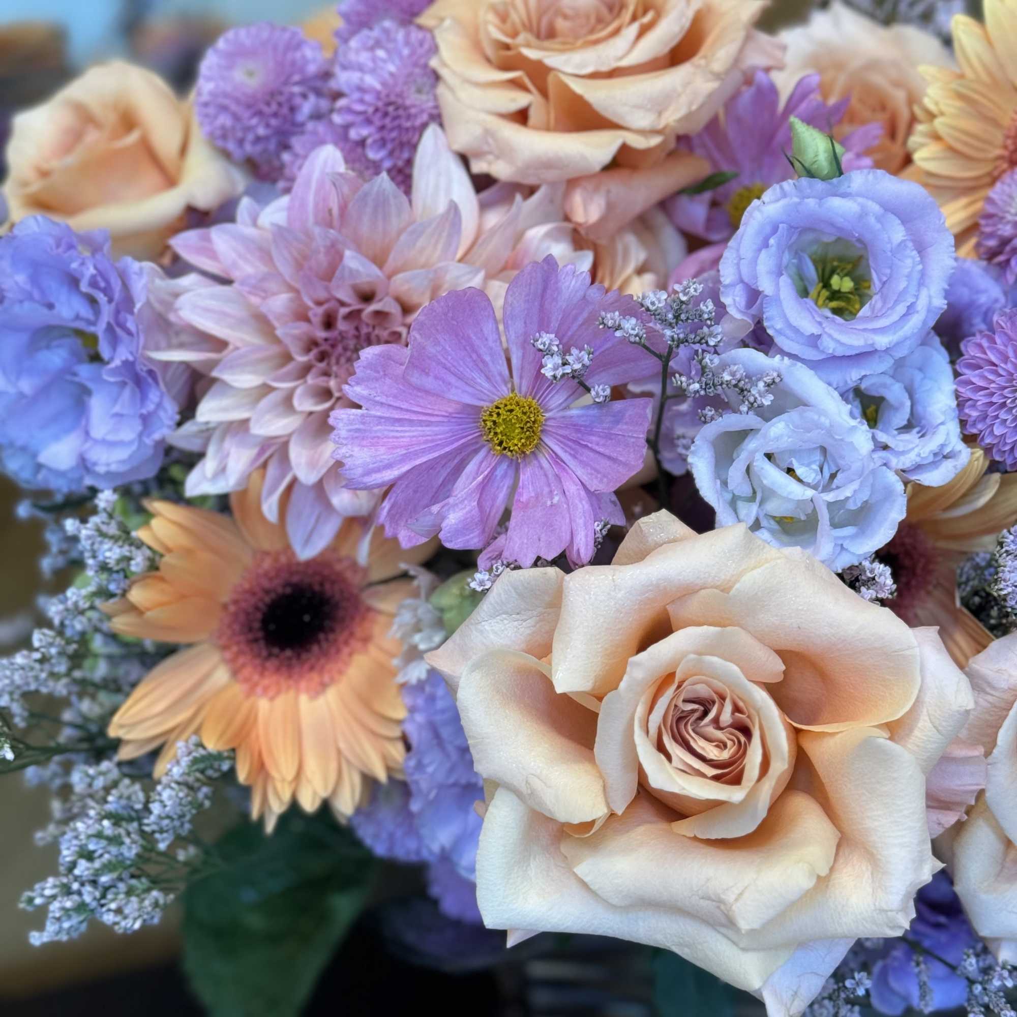 Bouquet of peach roses, lavender blooms, and pastel daisies