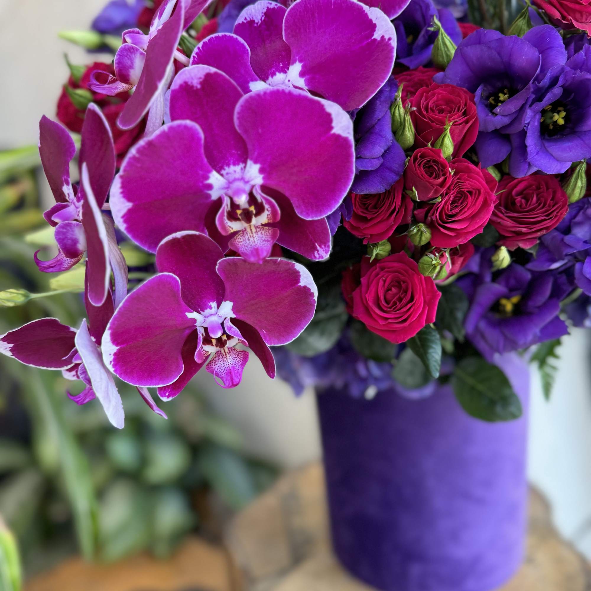 Bouquet of magenta orchids and pink roses in a purple wrap
