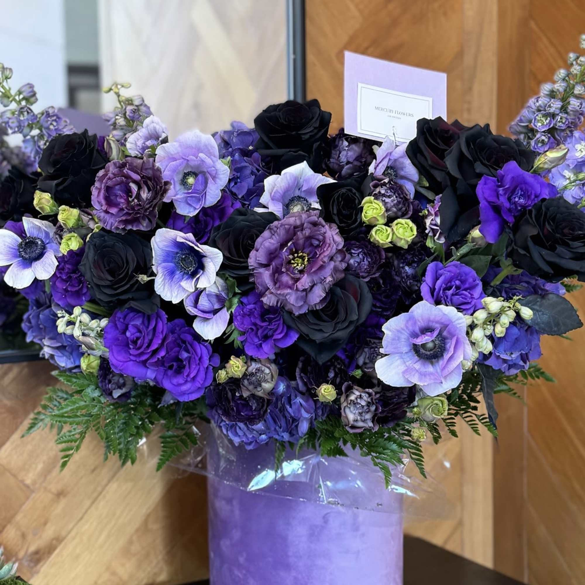 Purple and black floral arrangement in a lavender box