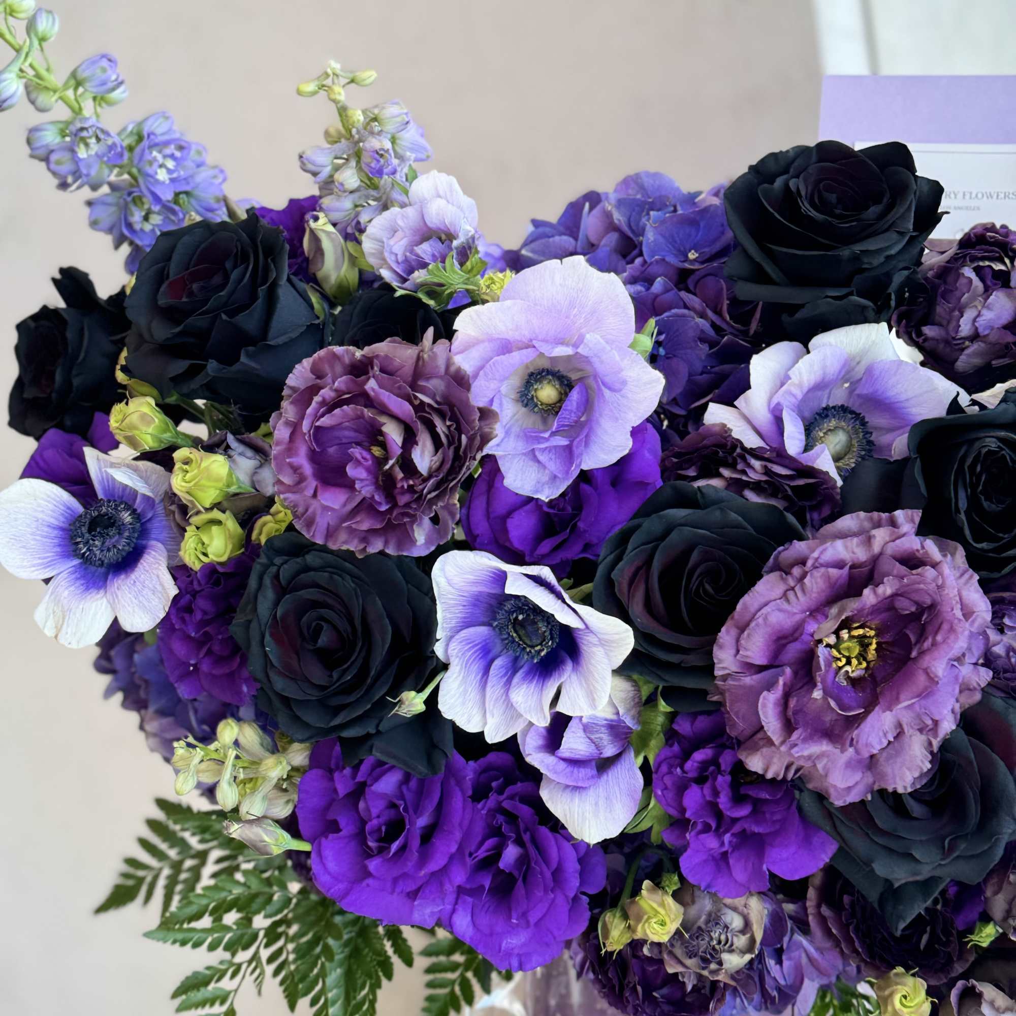 Bouquet of black, purple, and lavender flowers with fern accents