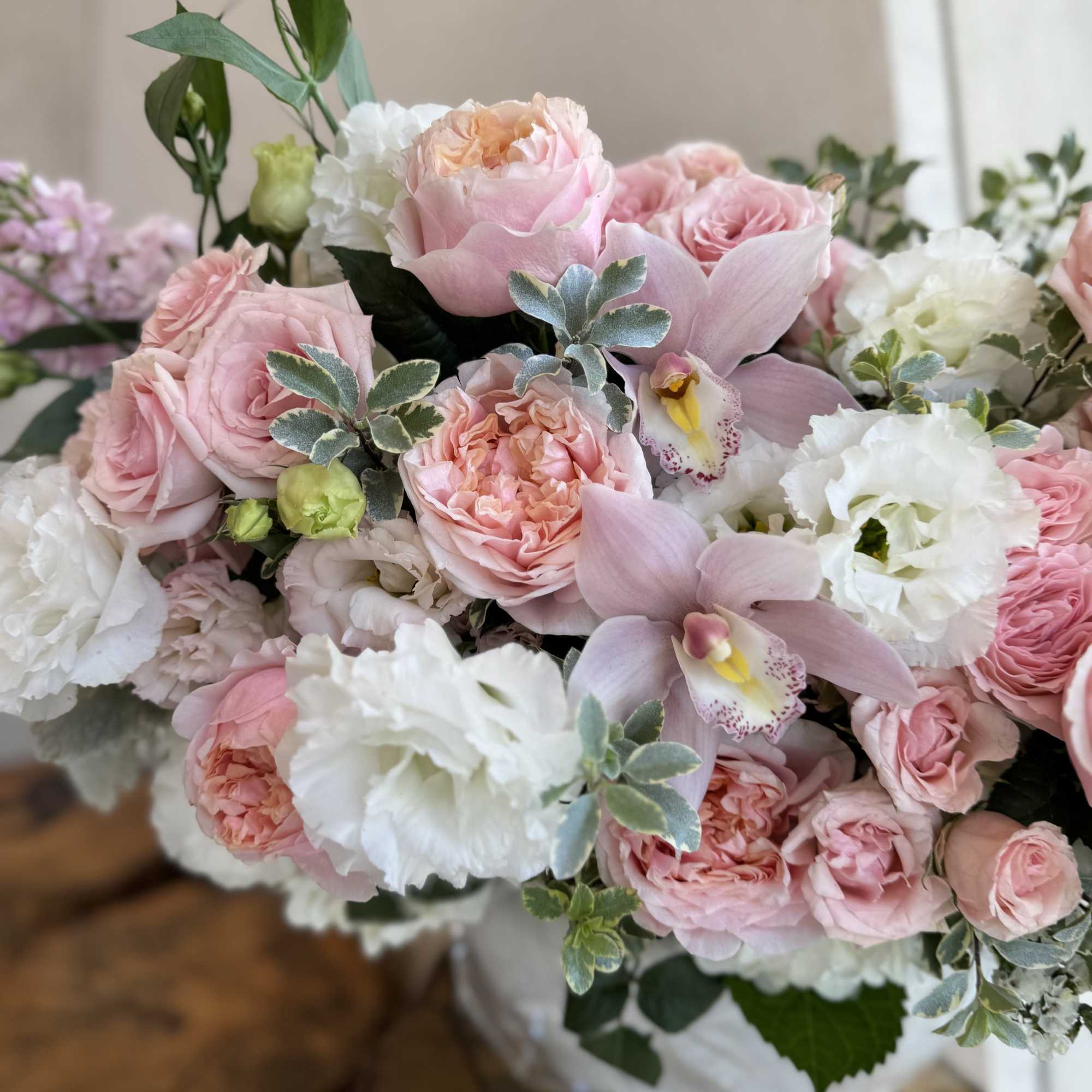 Pink and white bouquet with roses, orchids, and ruffled blooms
