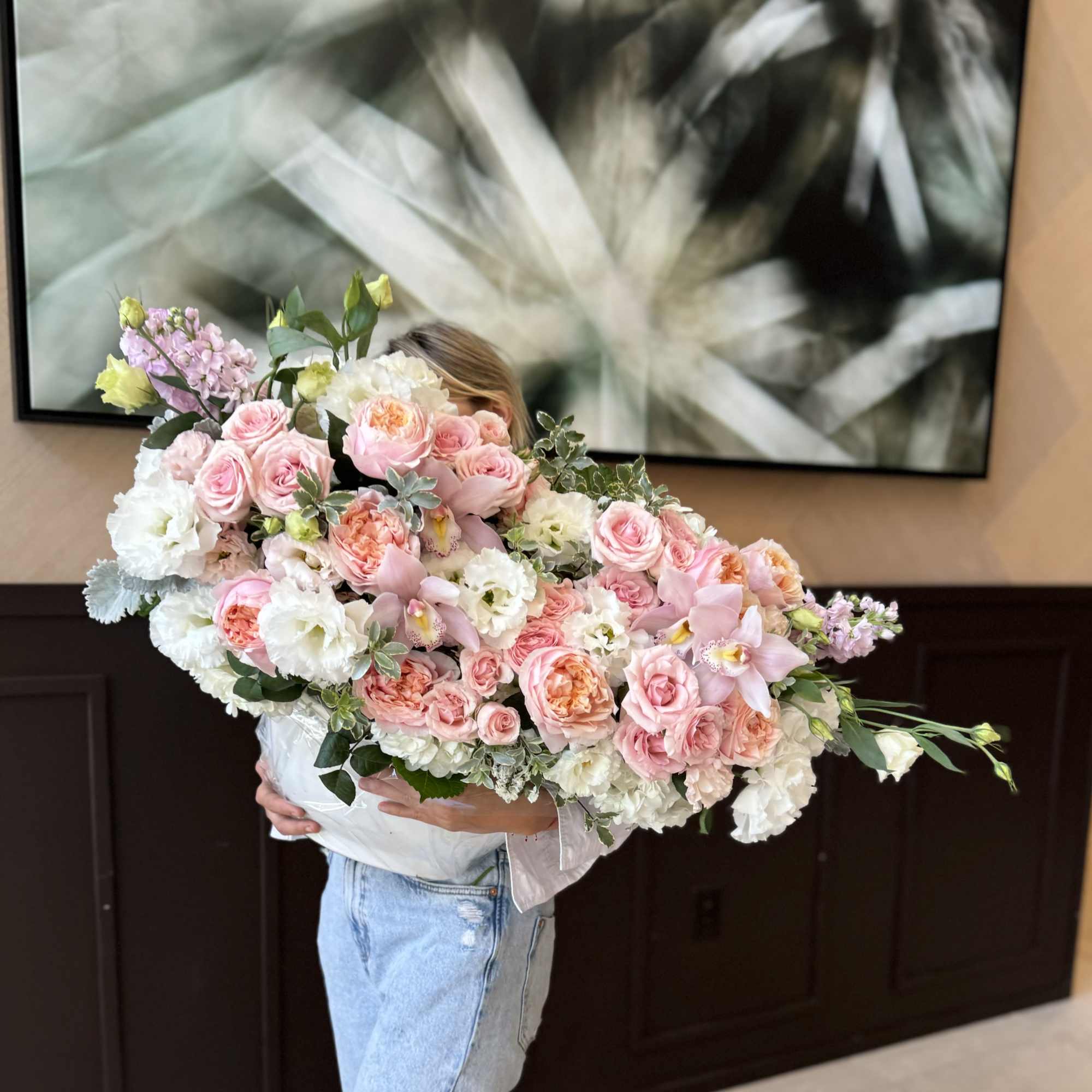 Large pastel bouquet of pink and white flowers held by a person