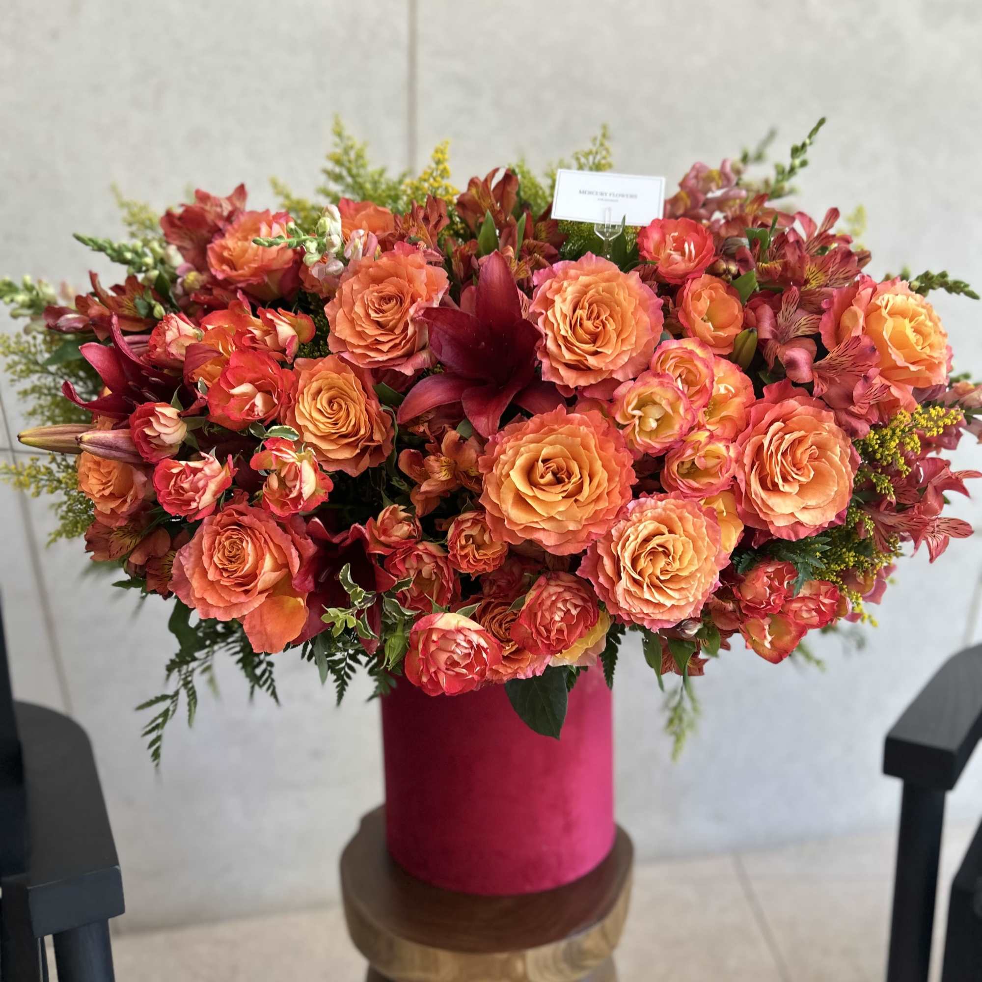 Large orange and pink floral arrangement in a magenta vase