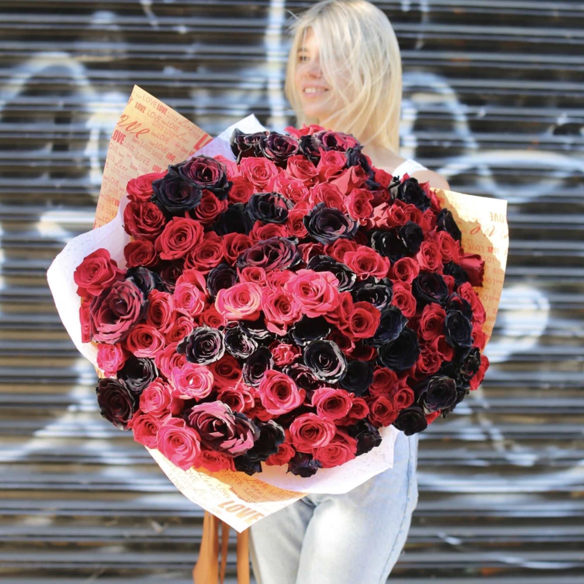 Large bouquet of pink and dark red roses wrapped in printed paper