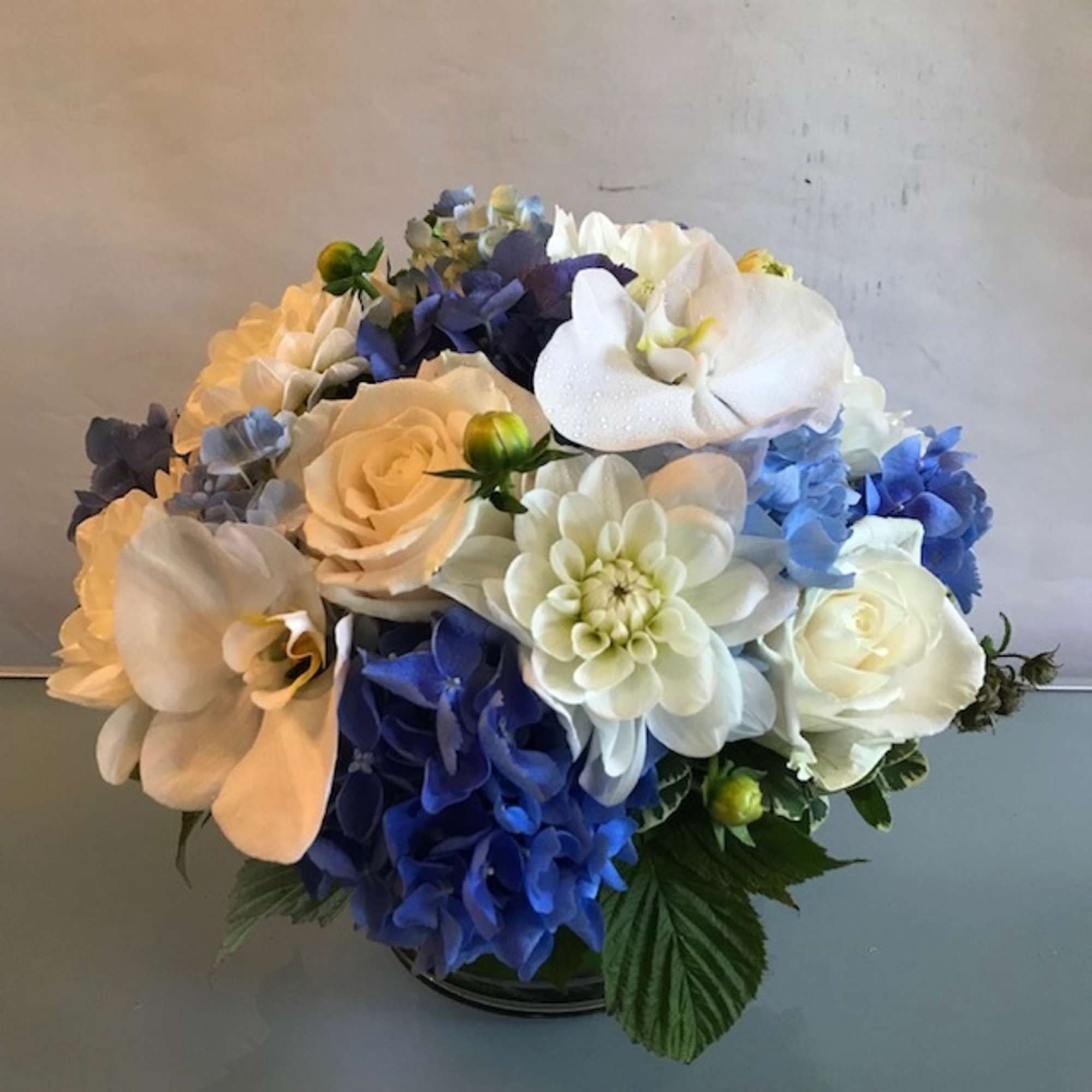 Bouquet of white, blue, and cream flowers in a low vase