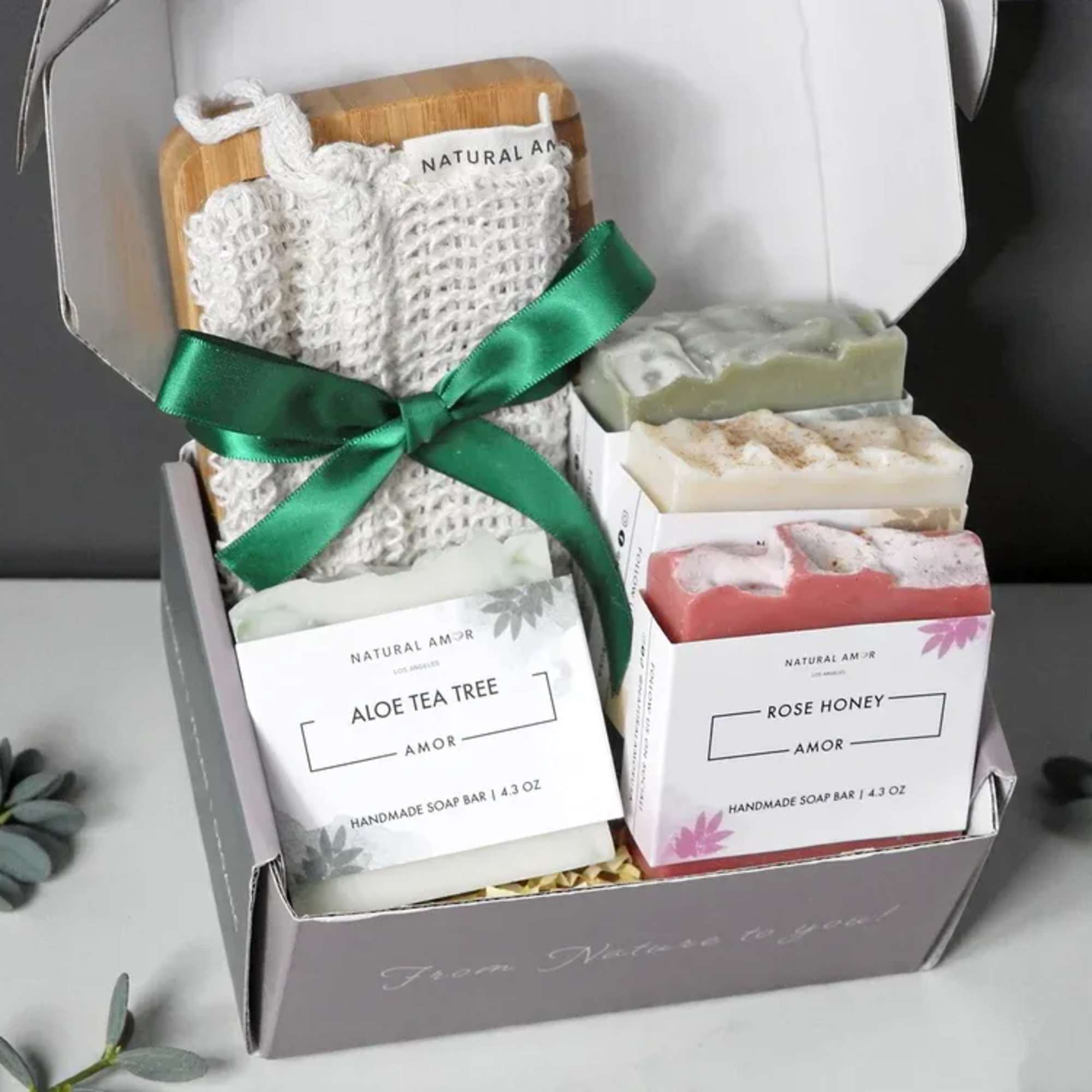 Gift box with handmade soap bars and a woven soap pouch tied with green ribbon