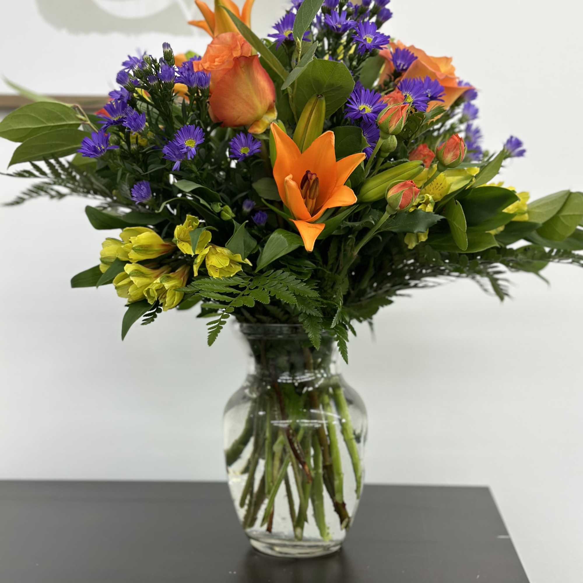 This sunny and bright arrangement includes orange roses, orange spray roses, orange