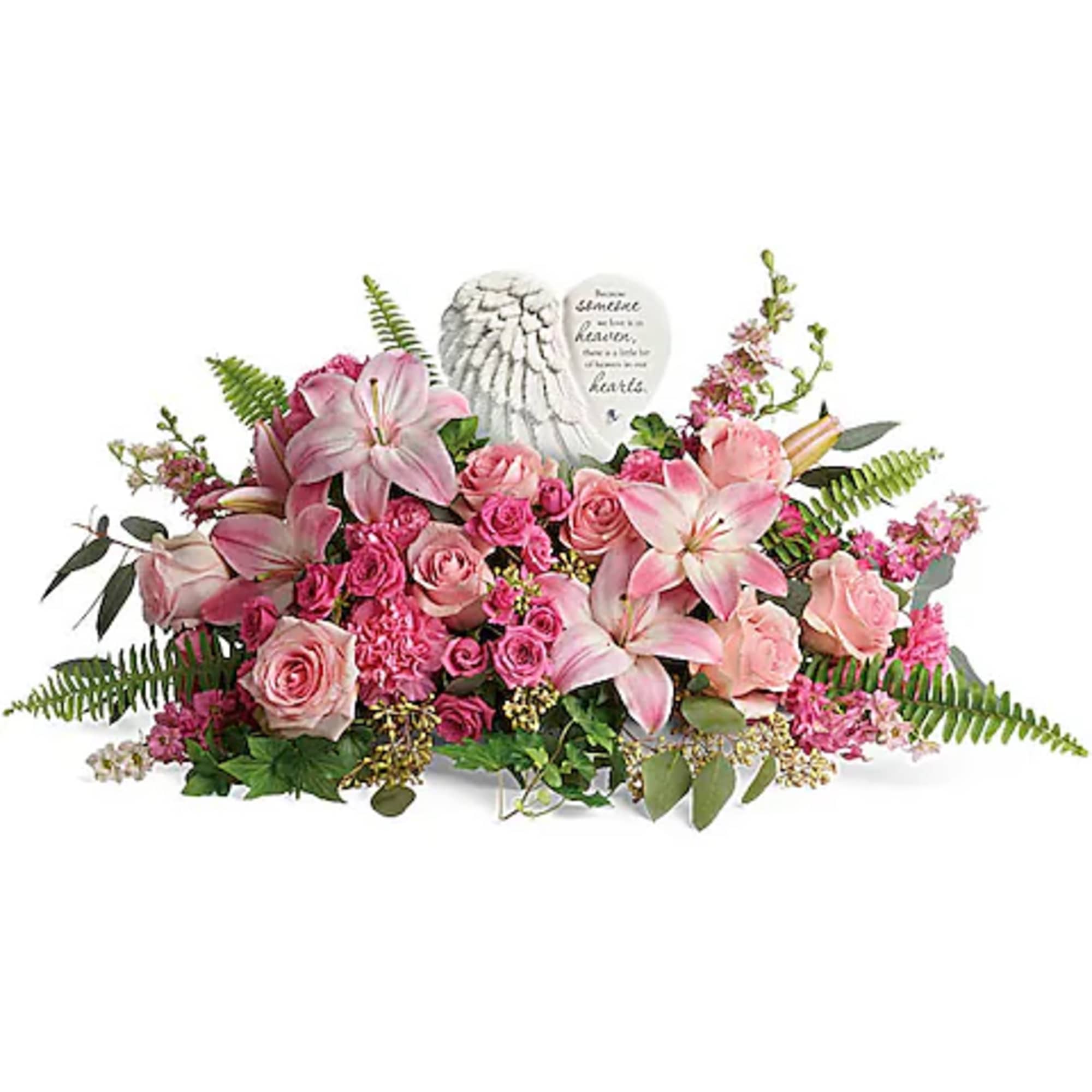 Pink roses and lilies arranged around a memorial stone plaque