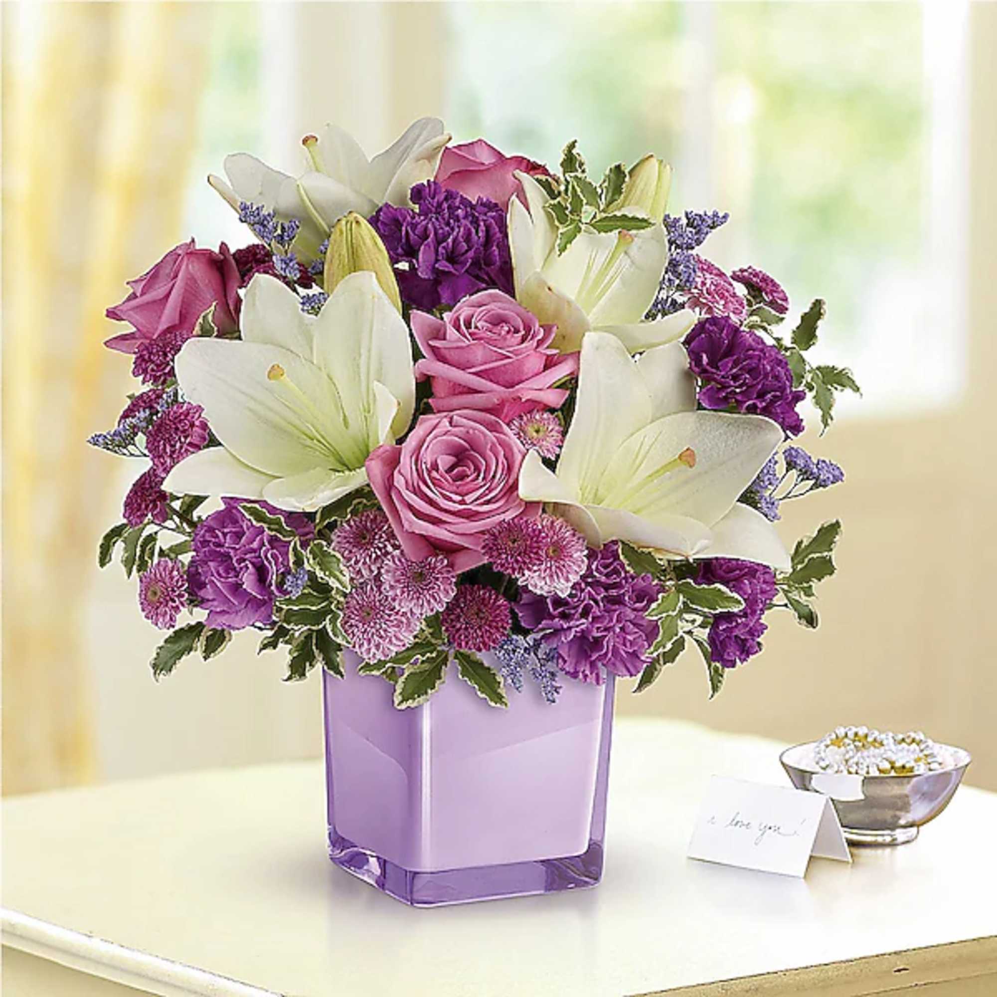 Pink roses and white lilies in a purple glass vase
