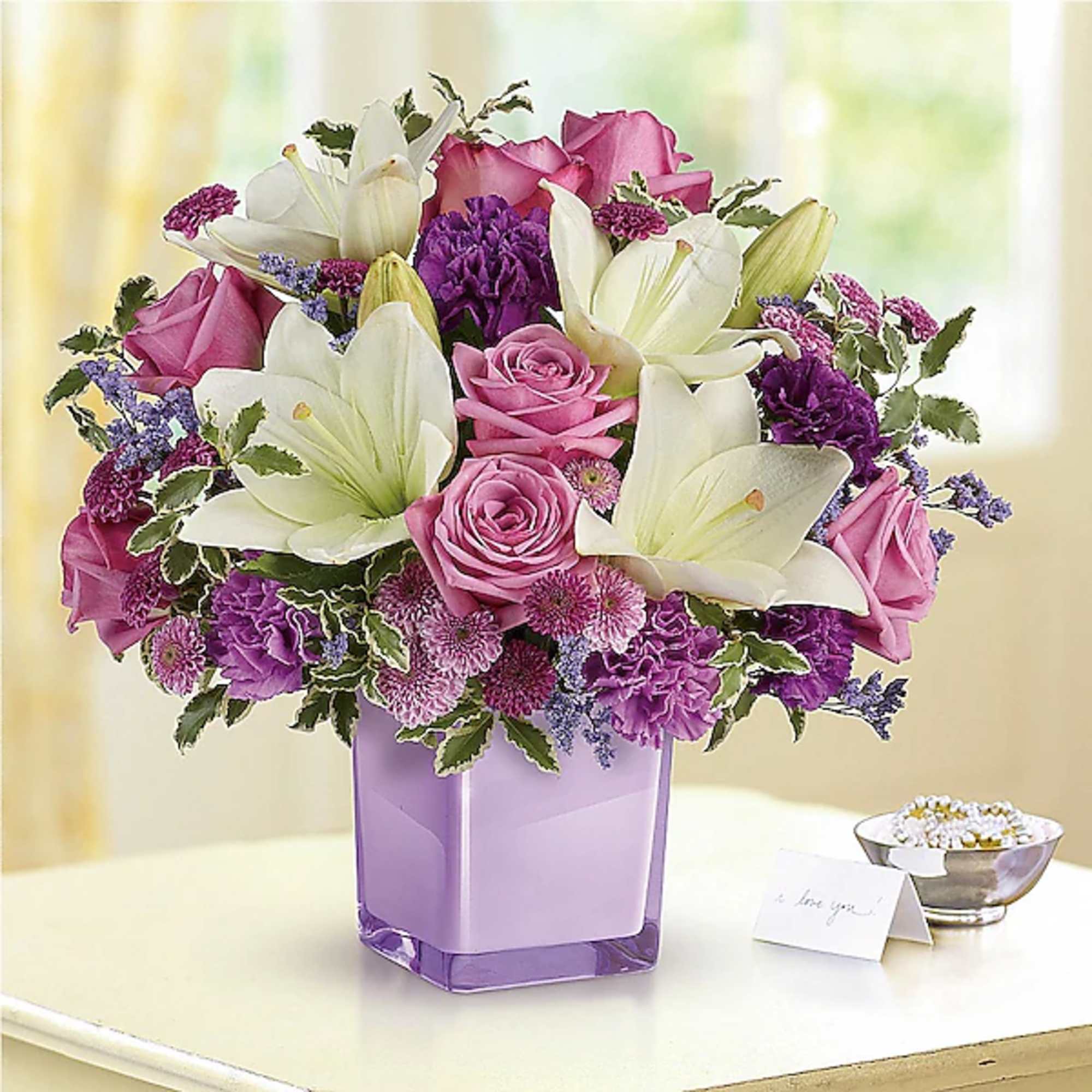Pink roses and white lilies in a purple glass vase