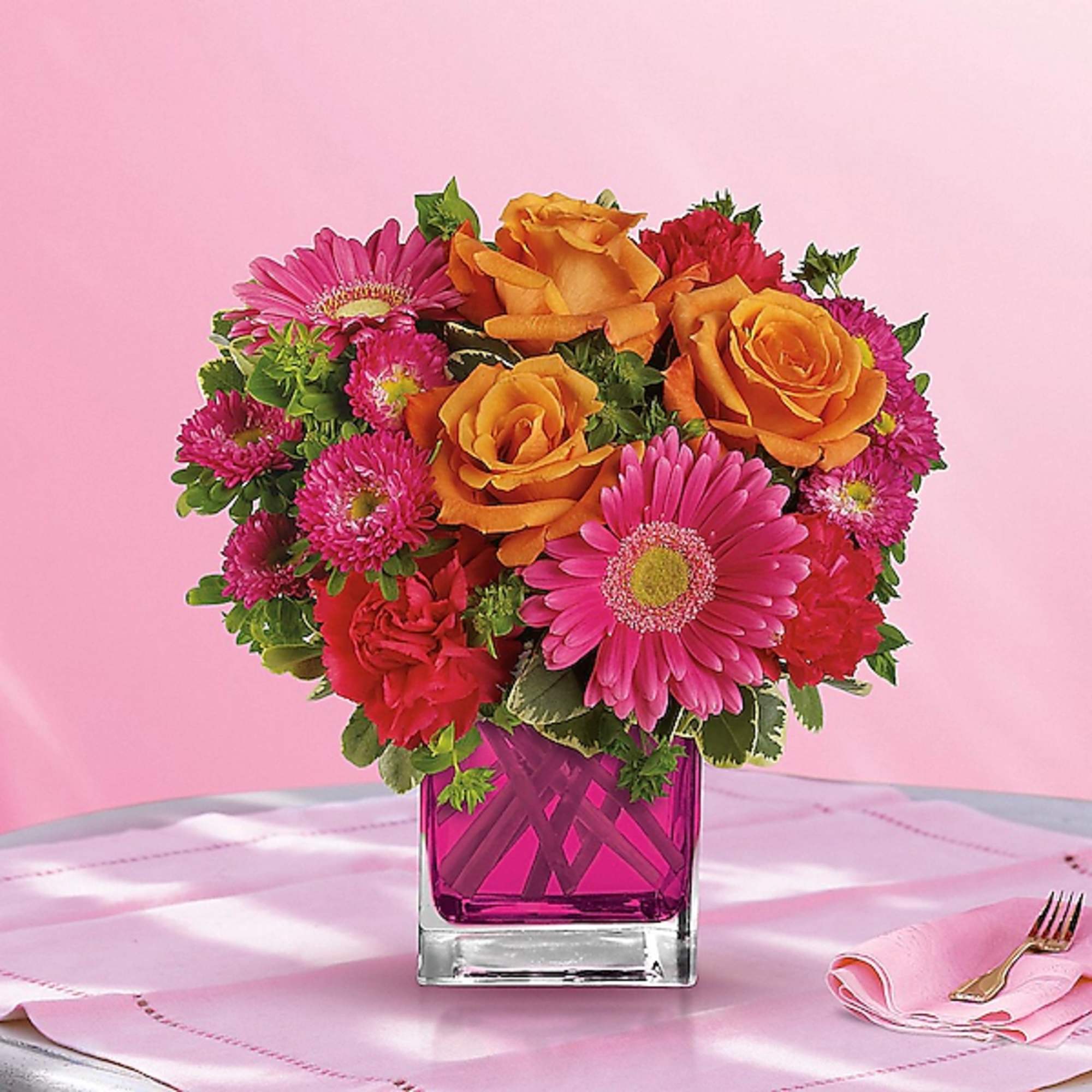 Pink and orange mixed bouquet in a magenta glass vase