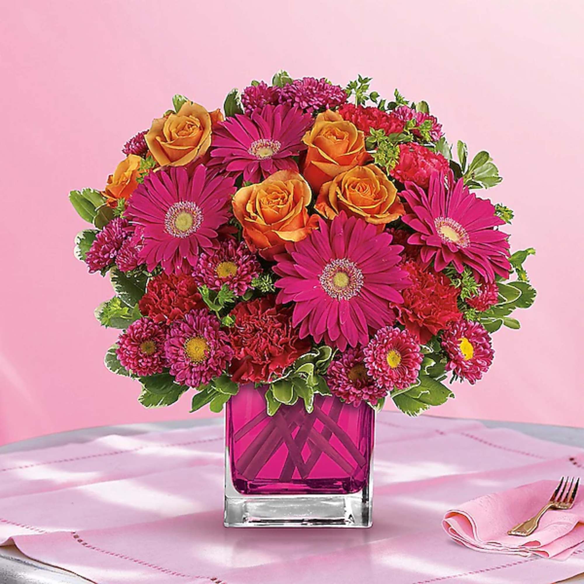 Pink and orange flower arrangement in a square glass vase