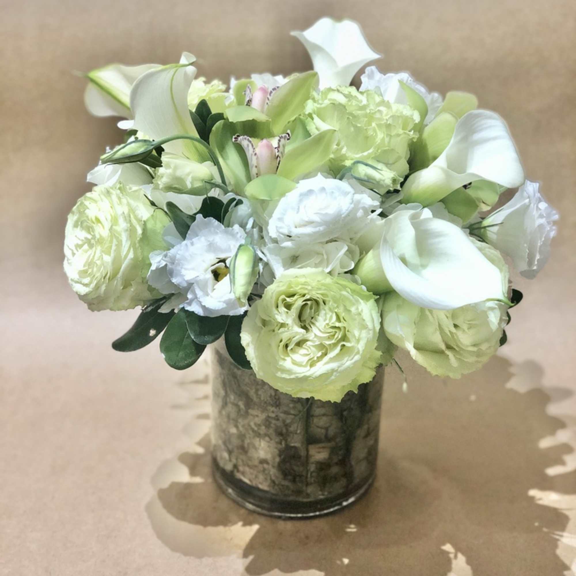 White and pale green floral arrangement in a glass vase