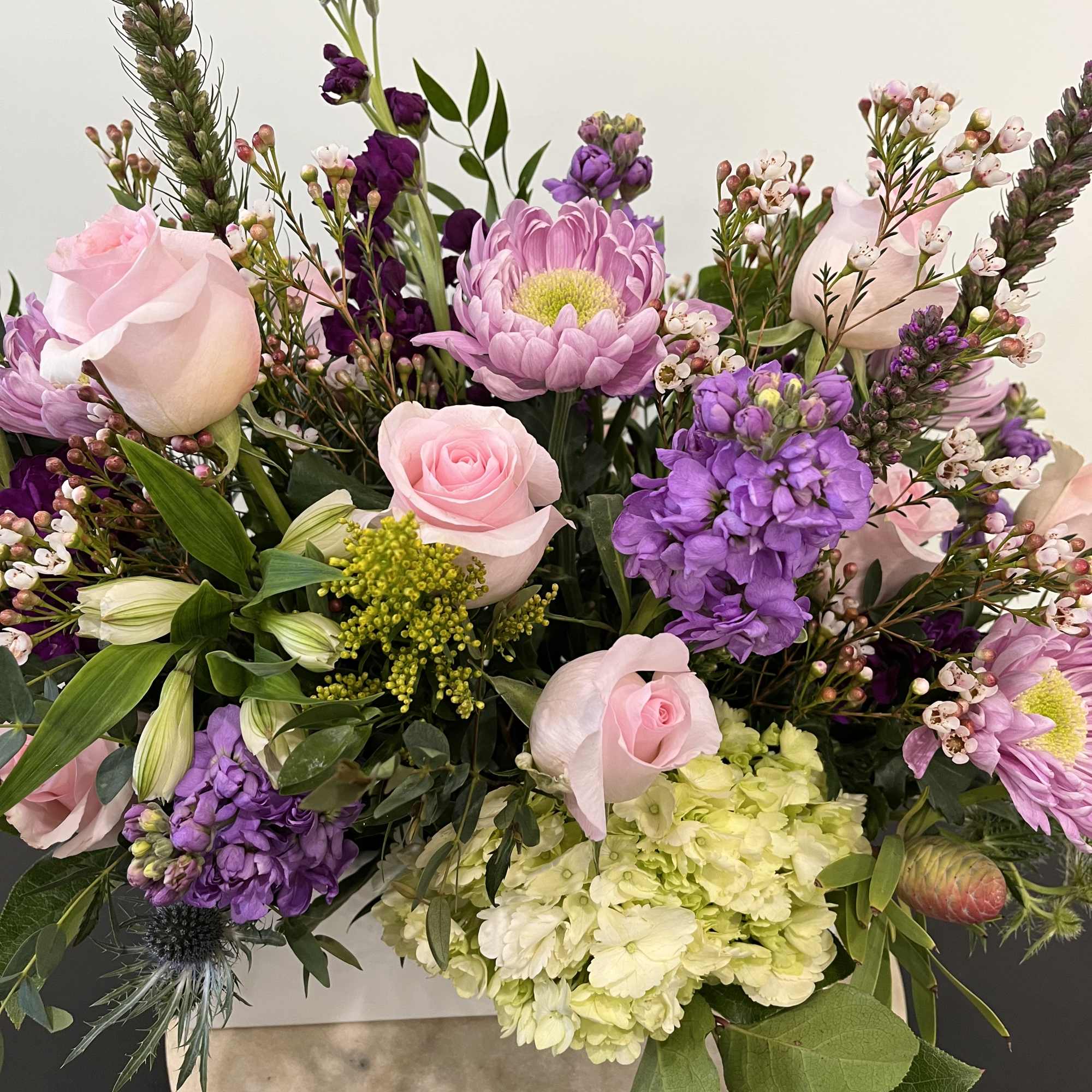 Mixed bouquet of pink roses, purple blooms, and pale hydrangeas