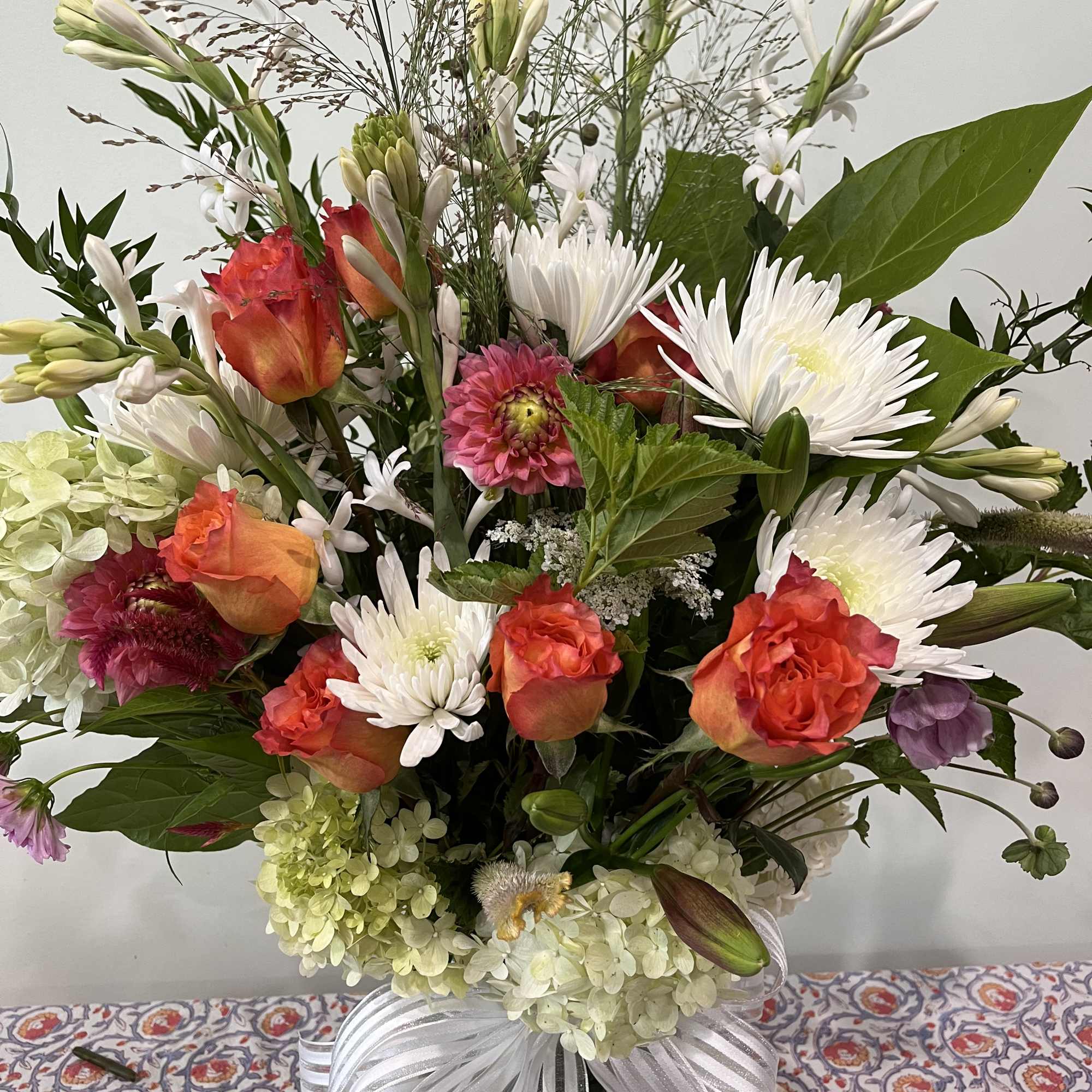 Mixed bouquet of orange roses, white chrysanthemums, and hydrangeas in a vase