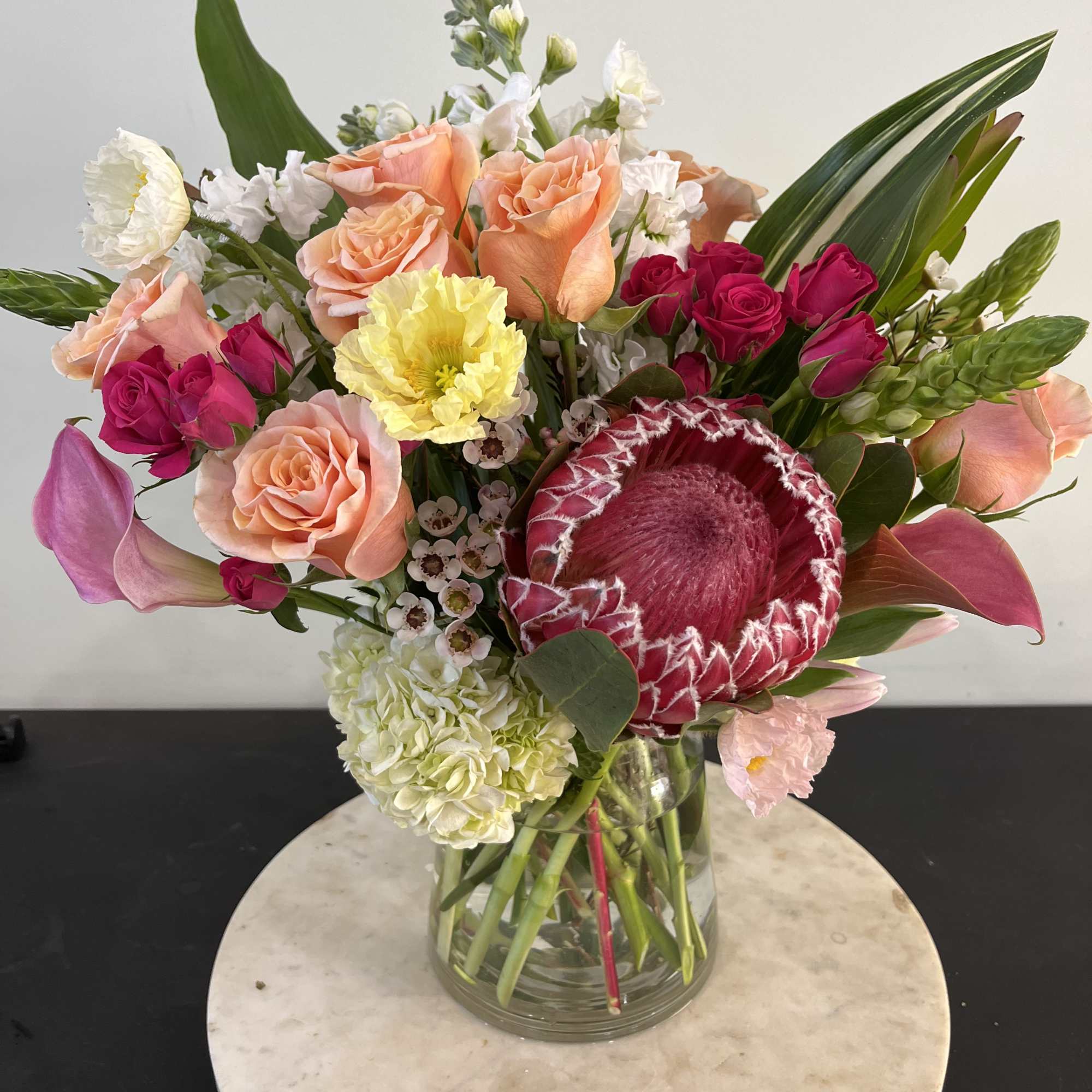Mixed bouquet of pink, peach, white, and yellow flowers in a glass vase