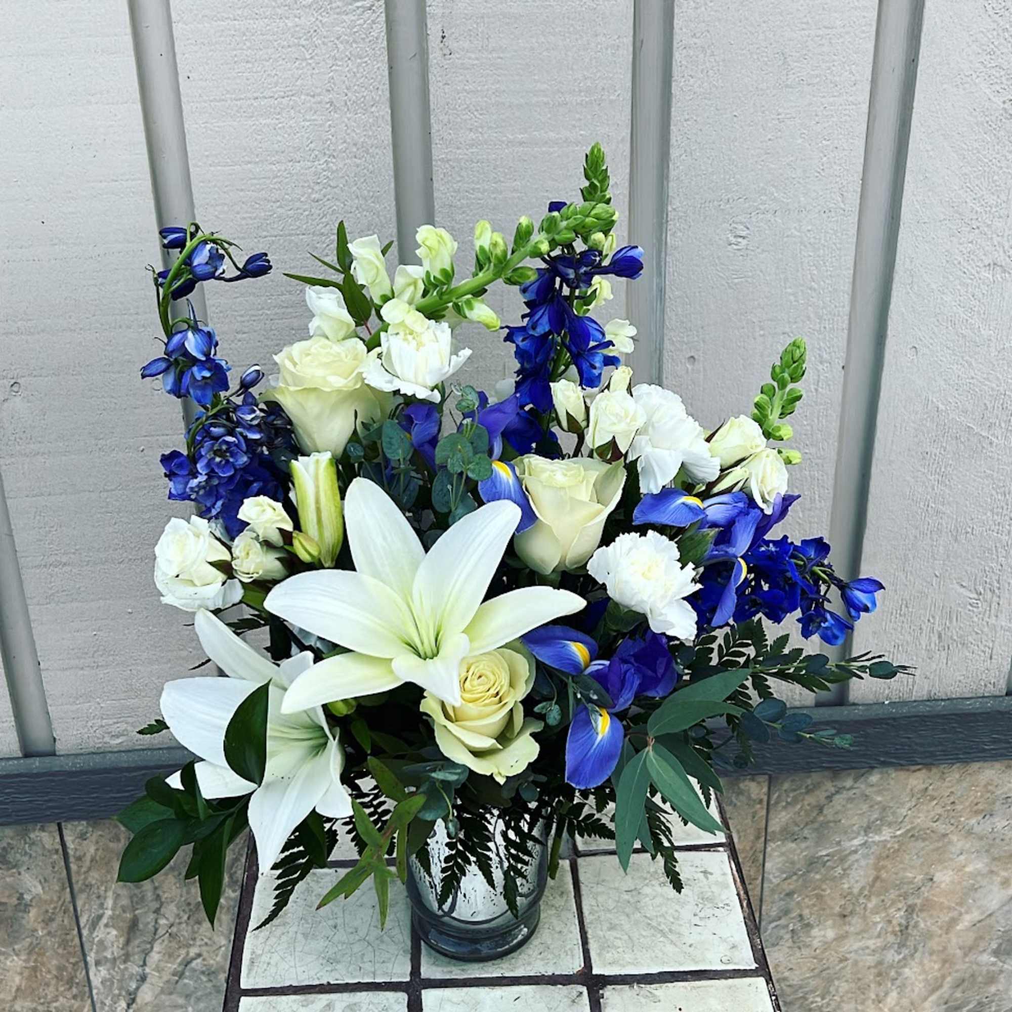 White lilies and blue flowers in a glass vase
