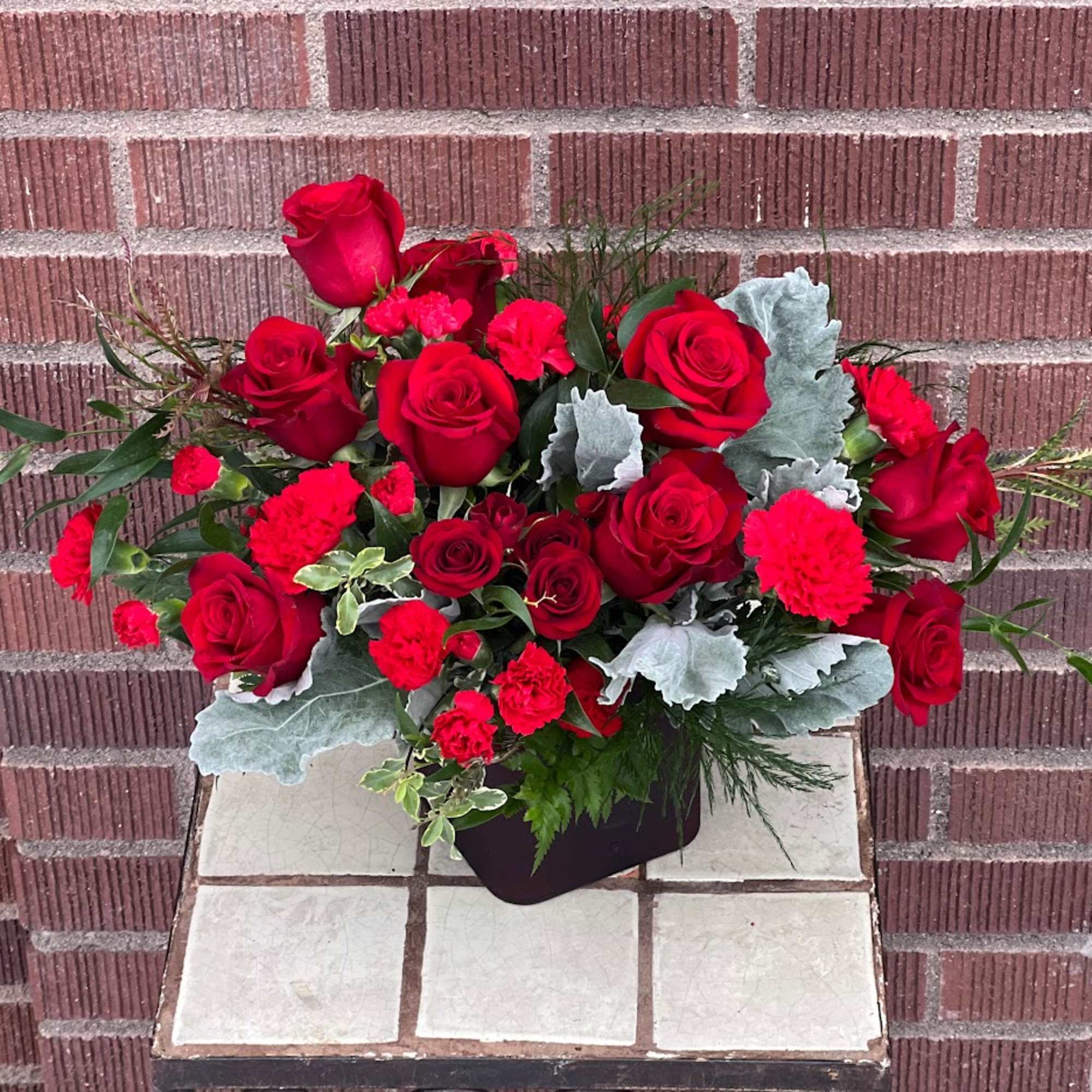 Red roses and carnations in a low black container