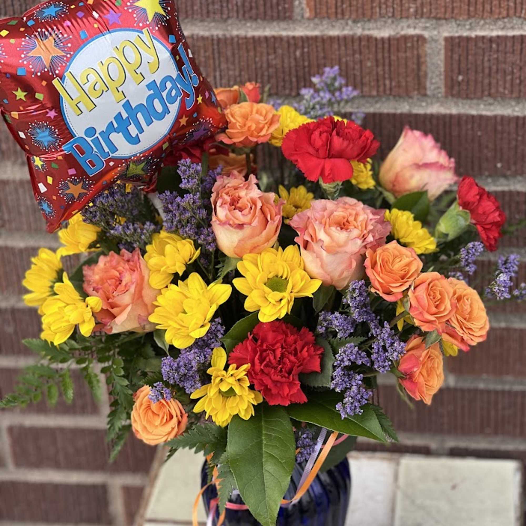 Birthday bouquet with roses, carnations, and a balloon in a vase