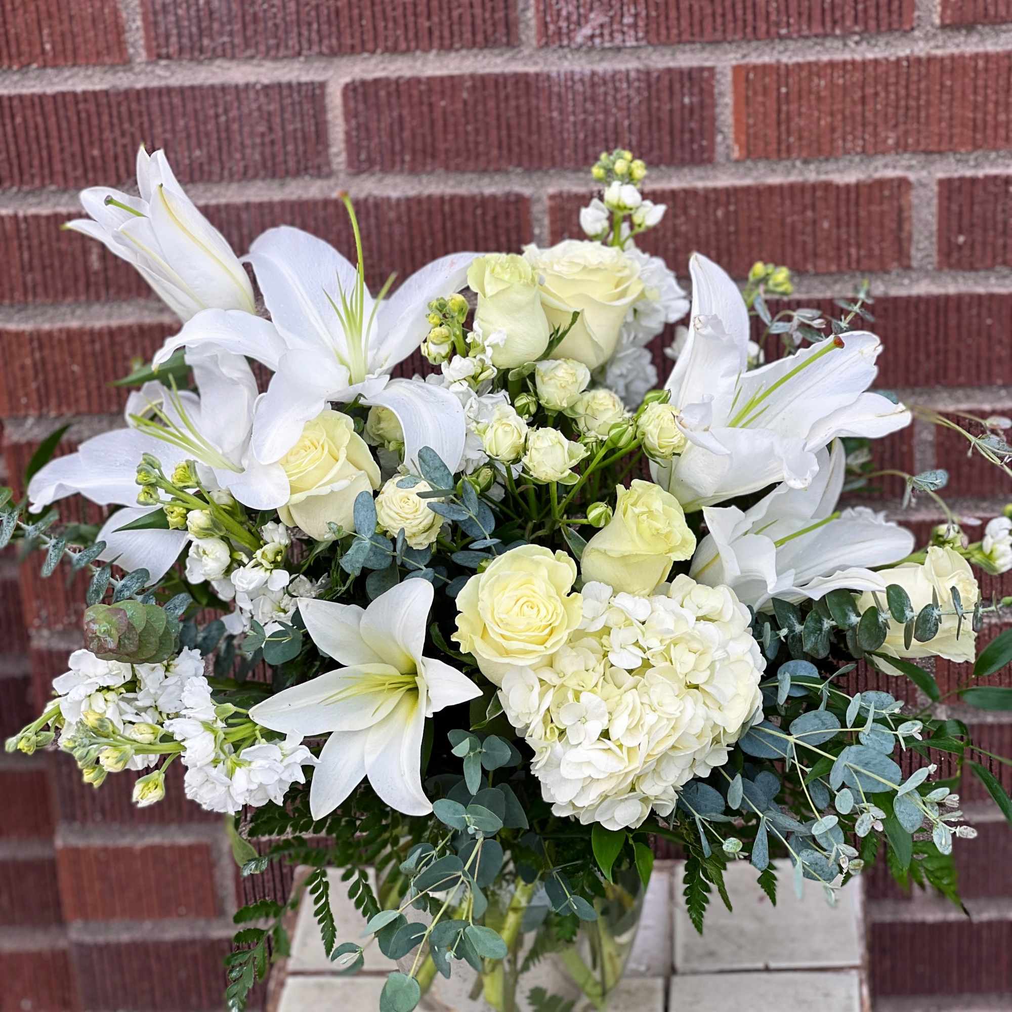White lilies and pale roses in a glass vase