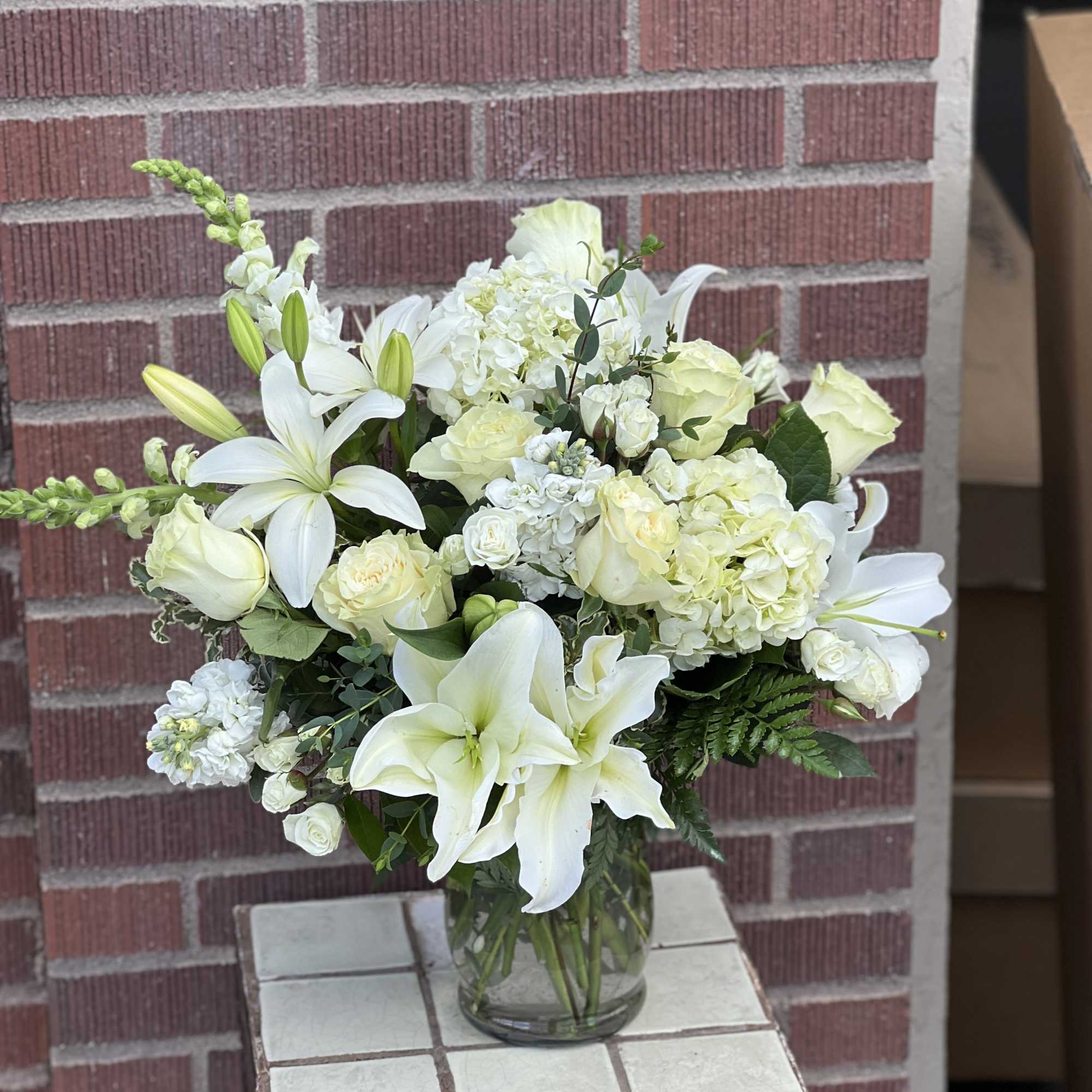 White lilies and pale roses arranged in a glass vase