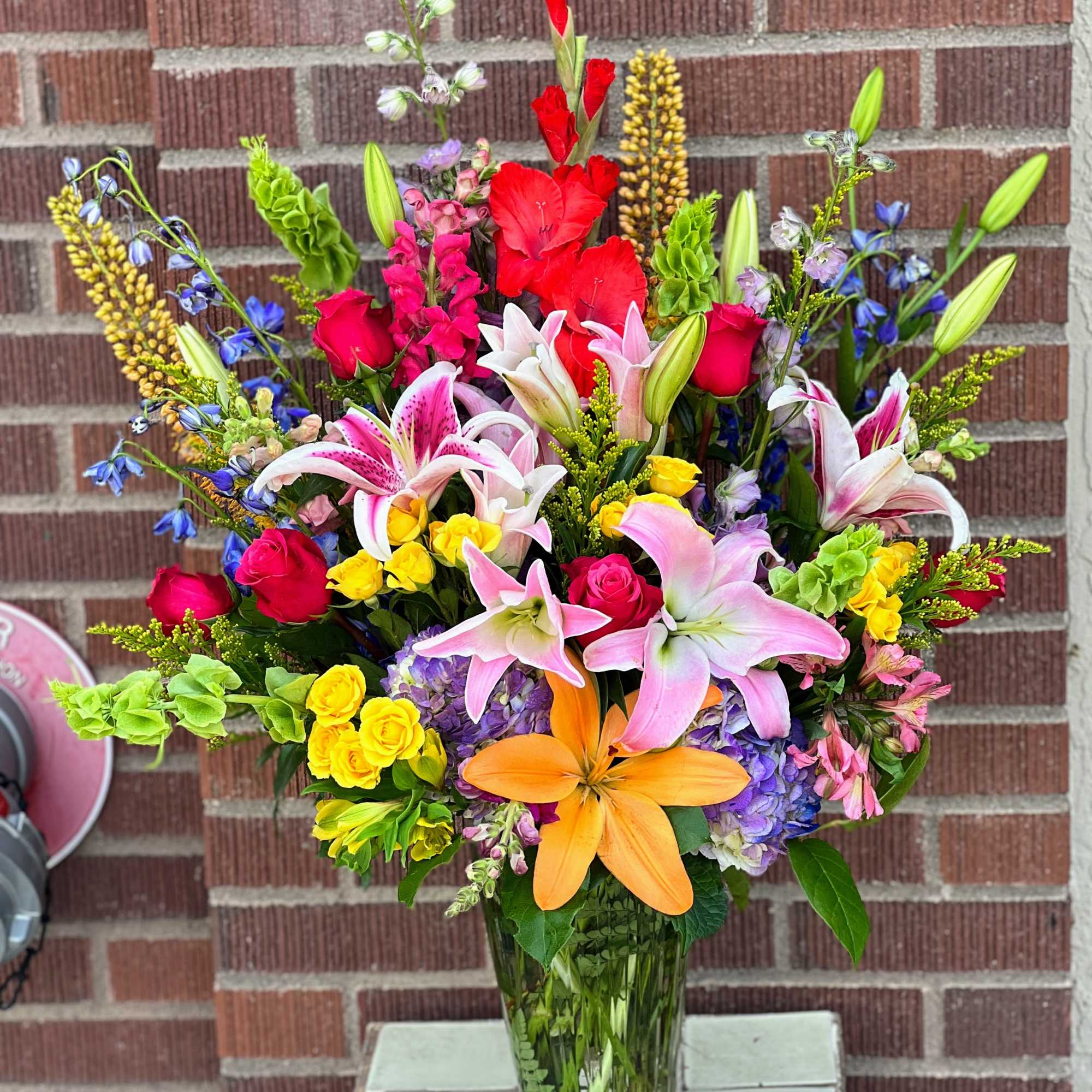 Colorful mixed bouquet with lilies, roses, and snapdragons in a glass vase