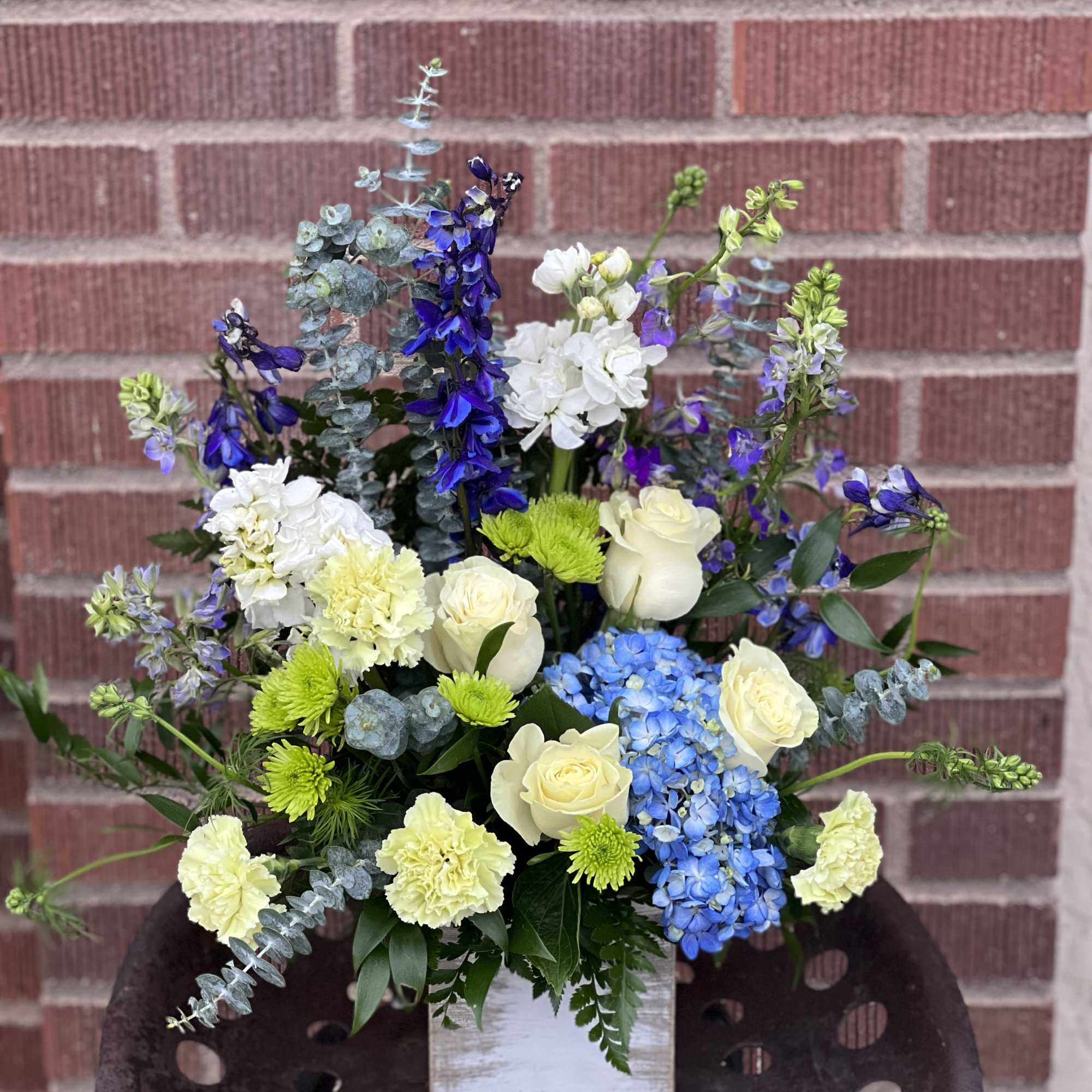 Mixed bouquet in a white wooden box with blue, white, and green flowers