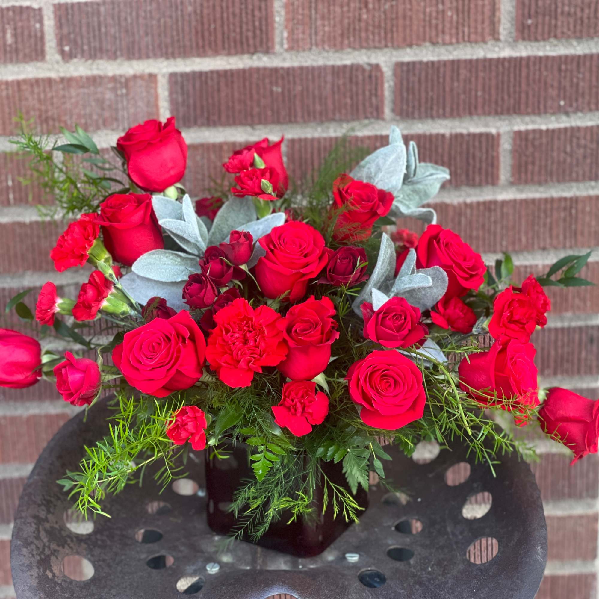 Red rose bouquet with carnations in a dark vase