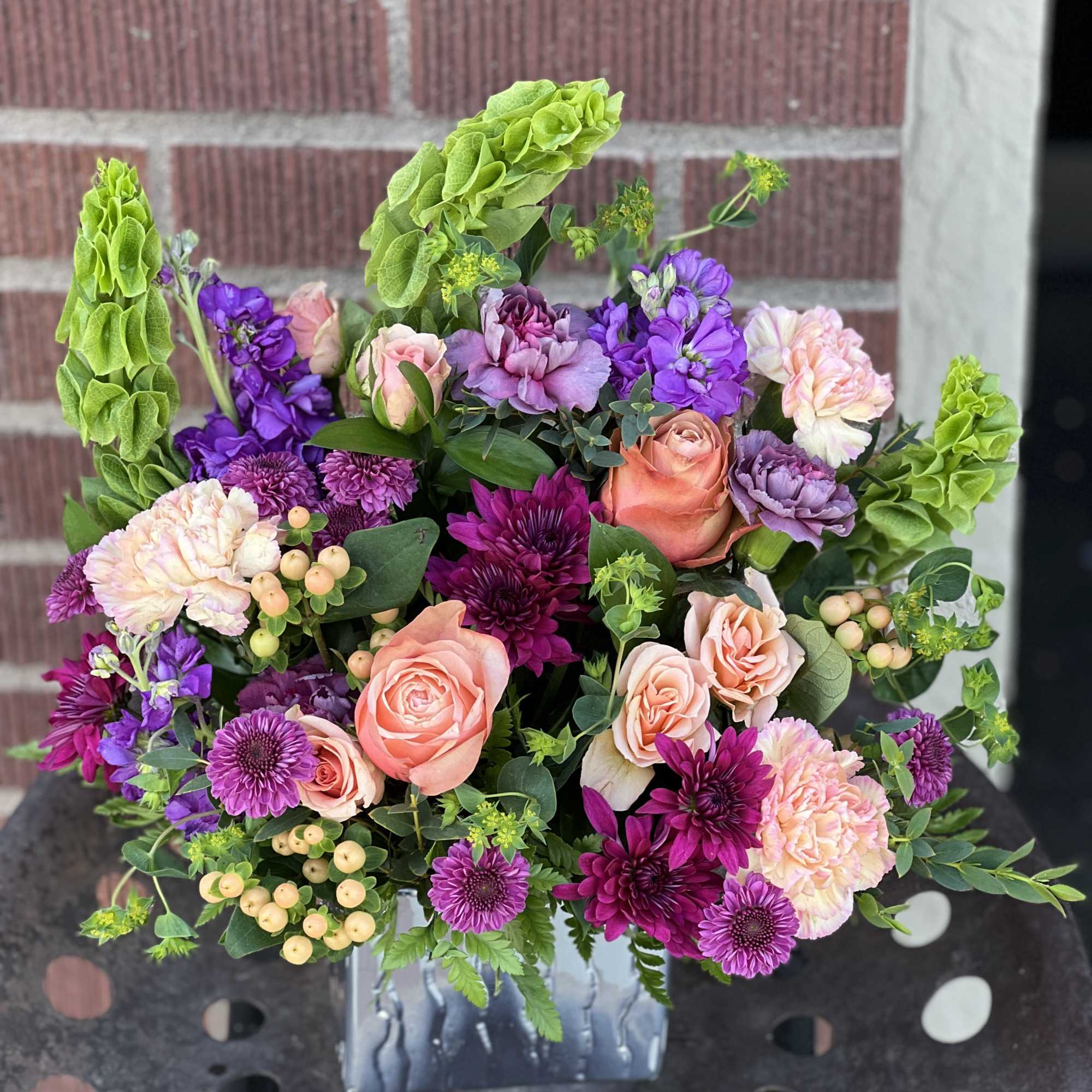 Mixed bouquet of pink, purple, and green flowers in a glass vase