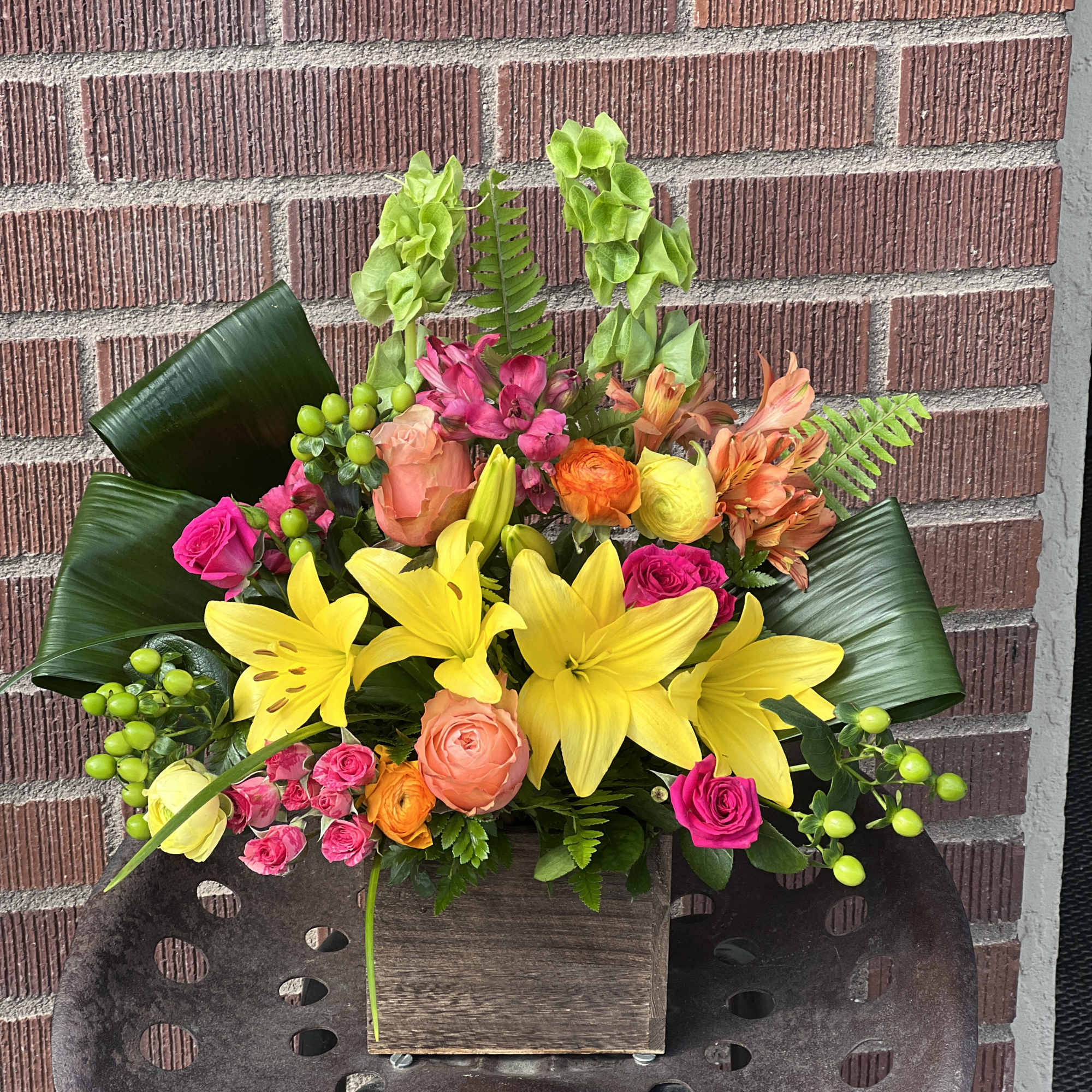 Bright mixed bouquet with yellow lilies and pink roses in a wooden box