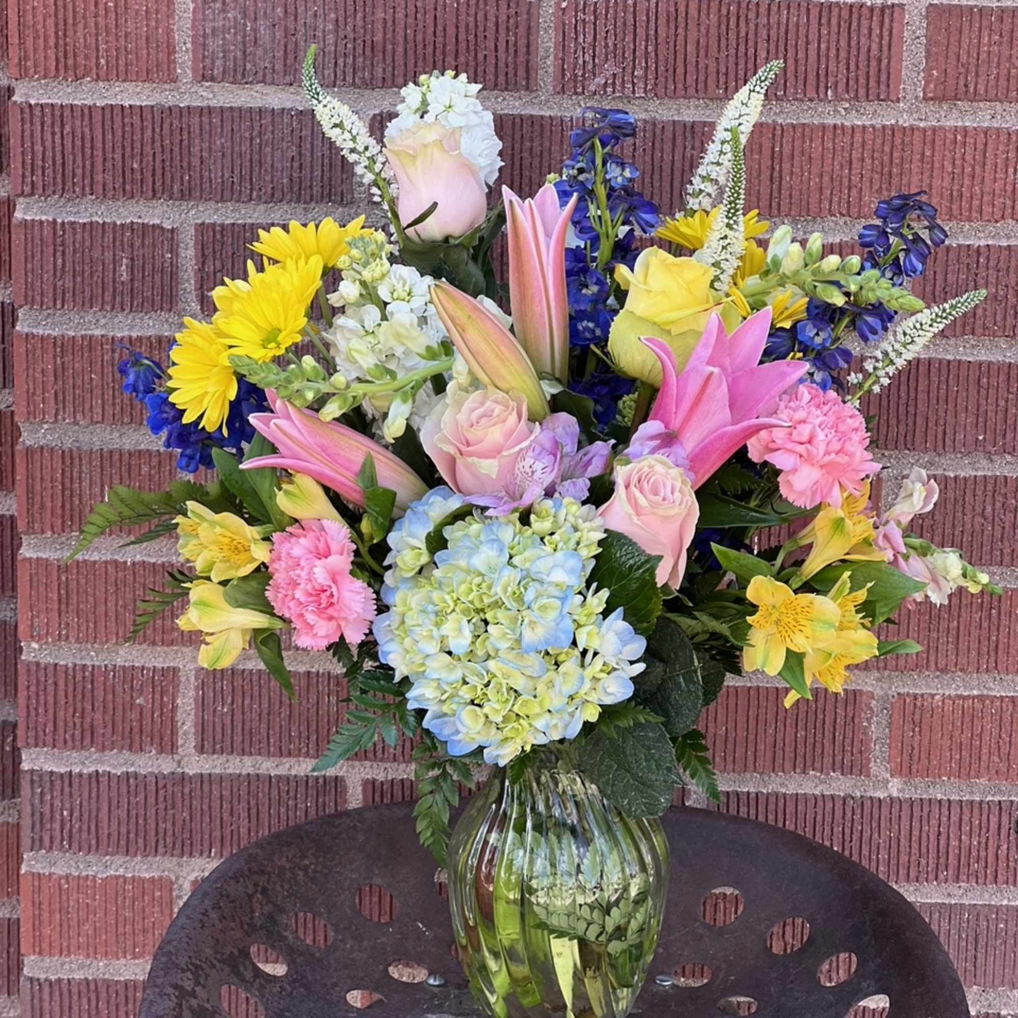 Mixed bouquet in a glass vase with pink, yellow, blue, and white flowers