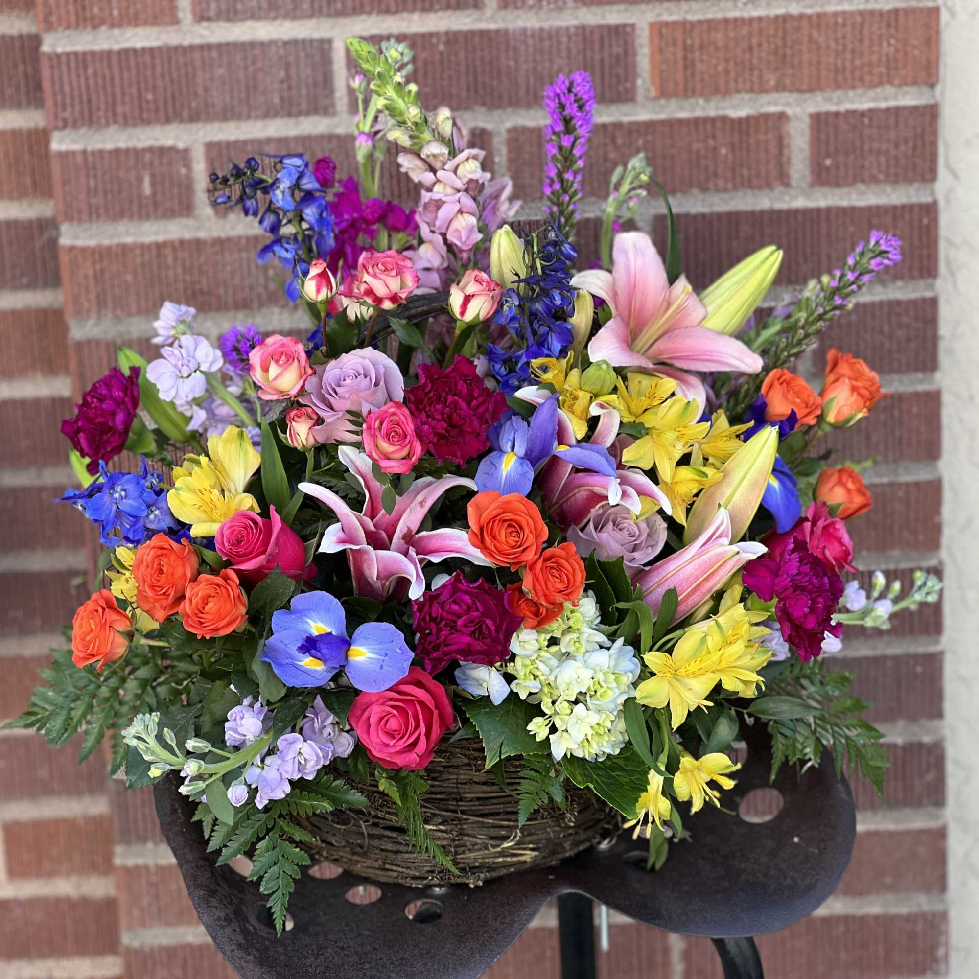 Colorful mixed flower arrangement in a woven basket on a stand