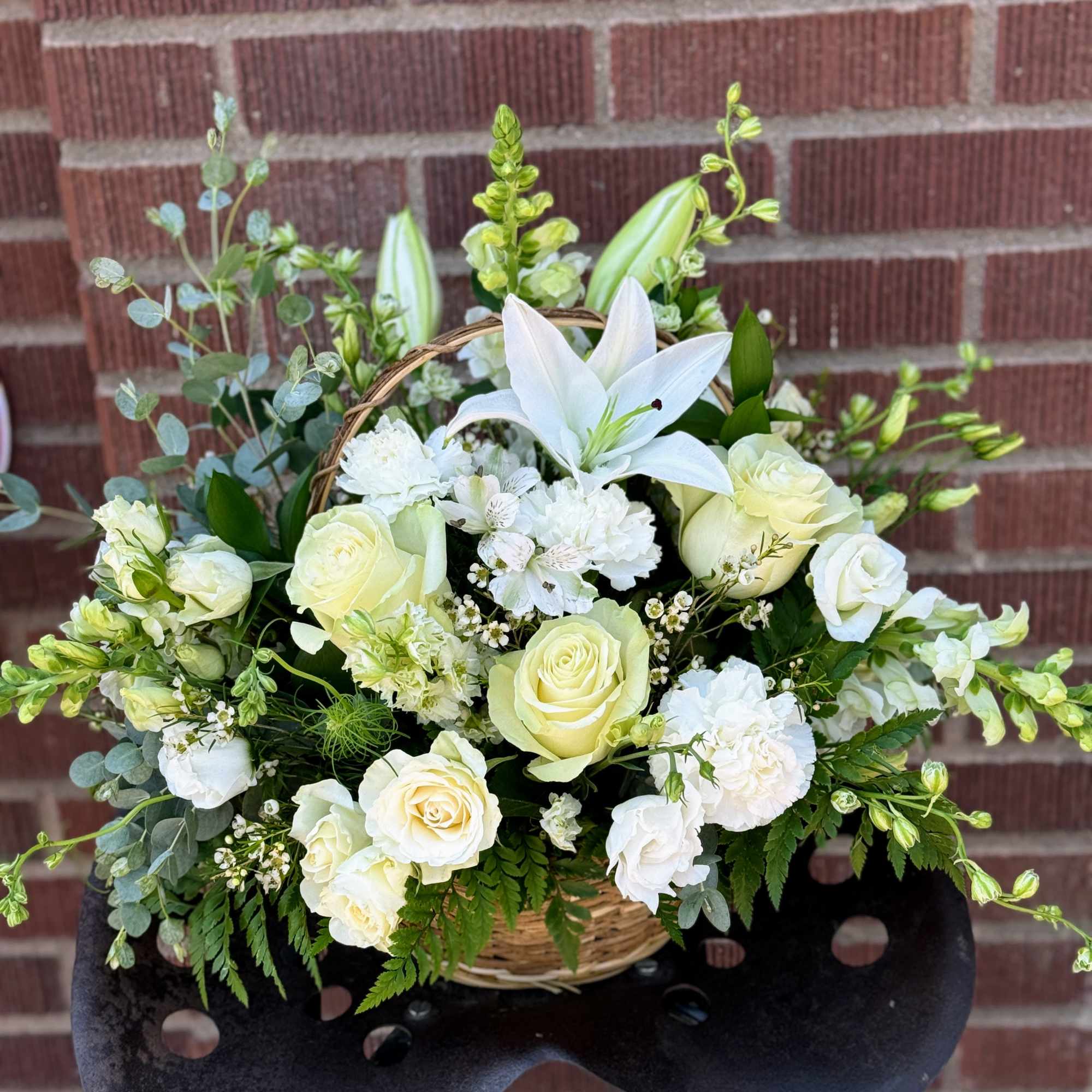White roses and lilies arranged in a wicker basket