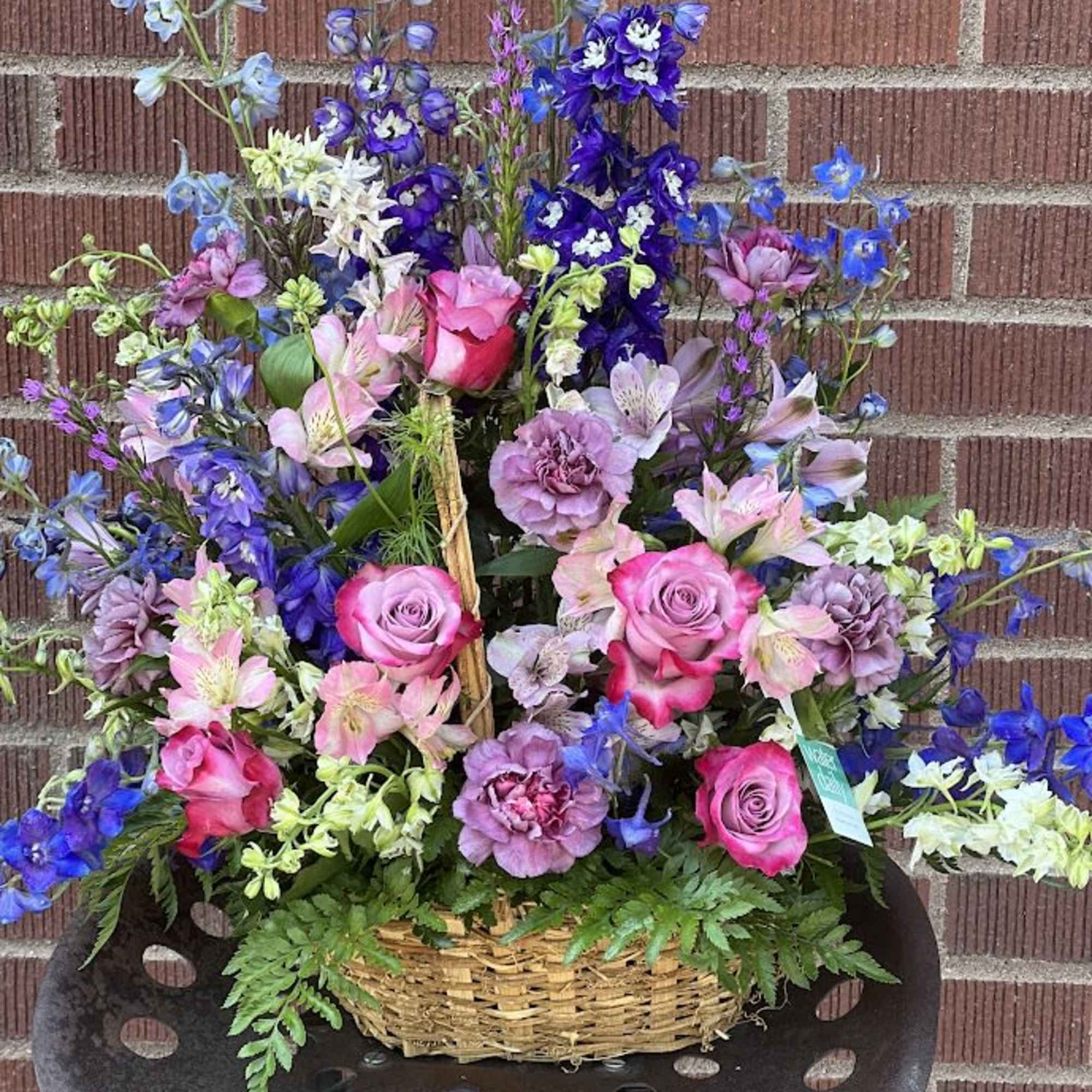 Basket arrangement of pink roses and blue-purple flowers