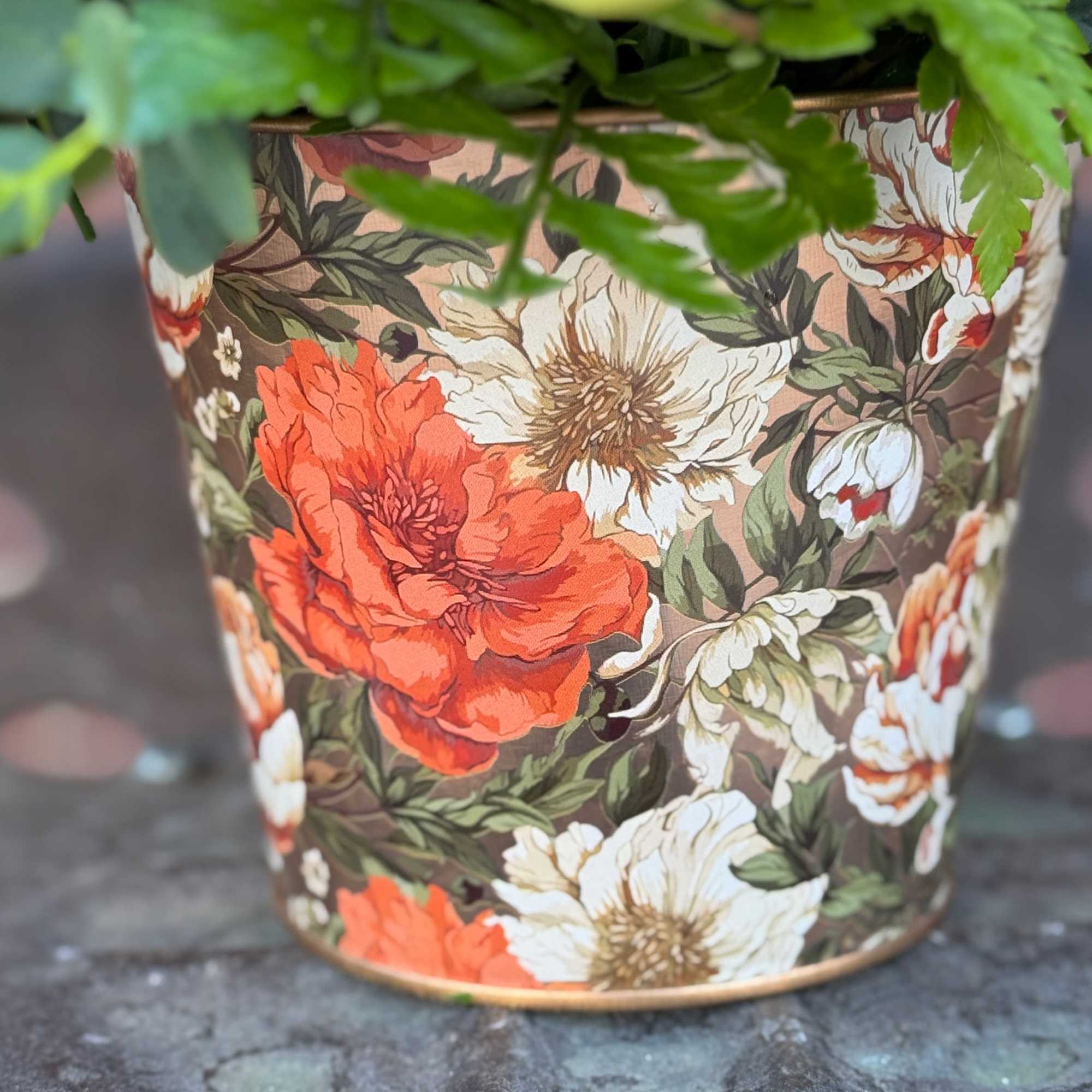 Floral-patterned planter with green foliage spilling over the top