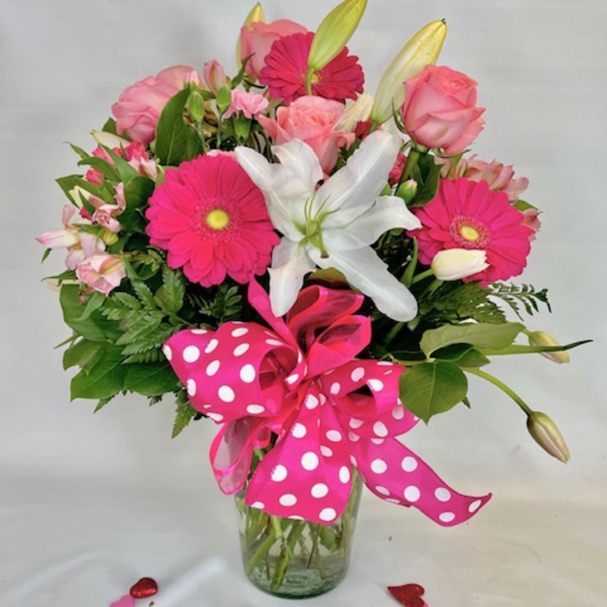 Pink and white mixed bouquet in a glass vase with a polka-dot ribbon