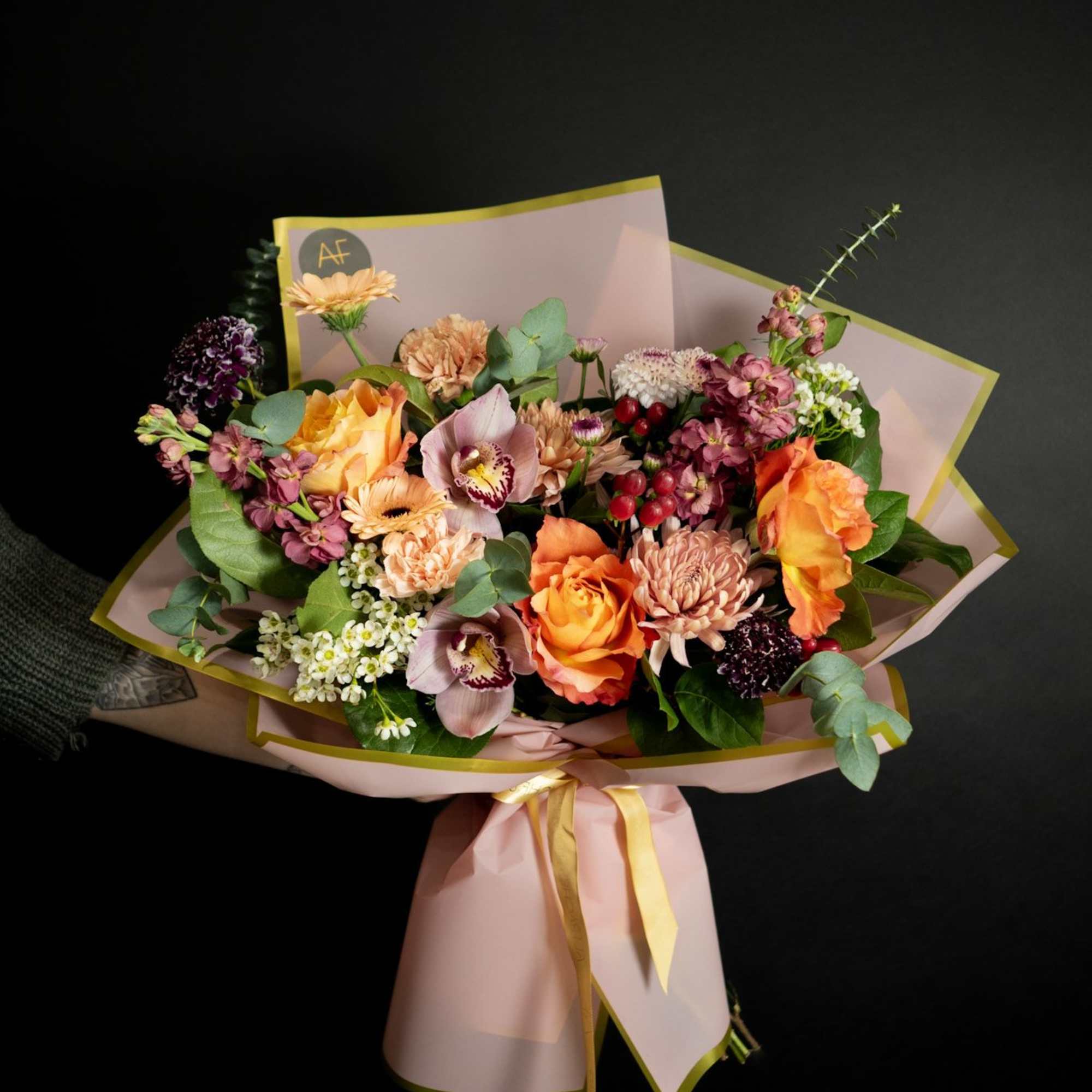 Bouquet of orange, pink, and purple flowers wrapped in pink paper