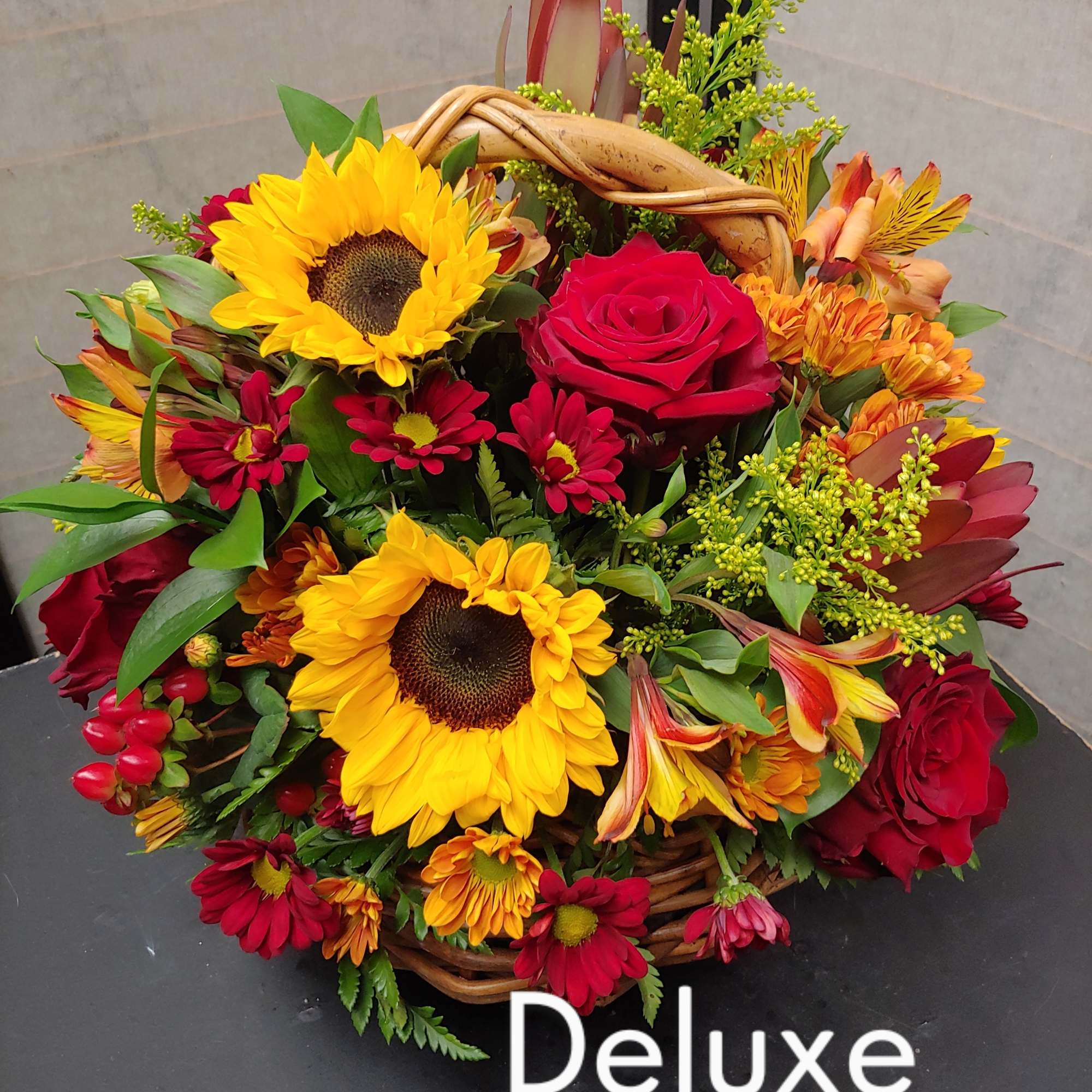Basket arrangement with sunflowers, red roses, and mixed autumn flowers