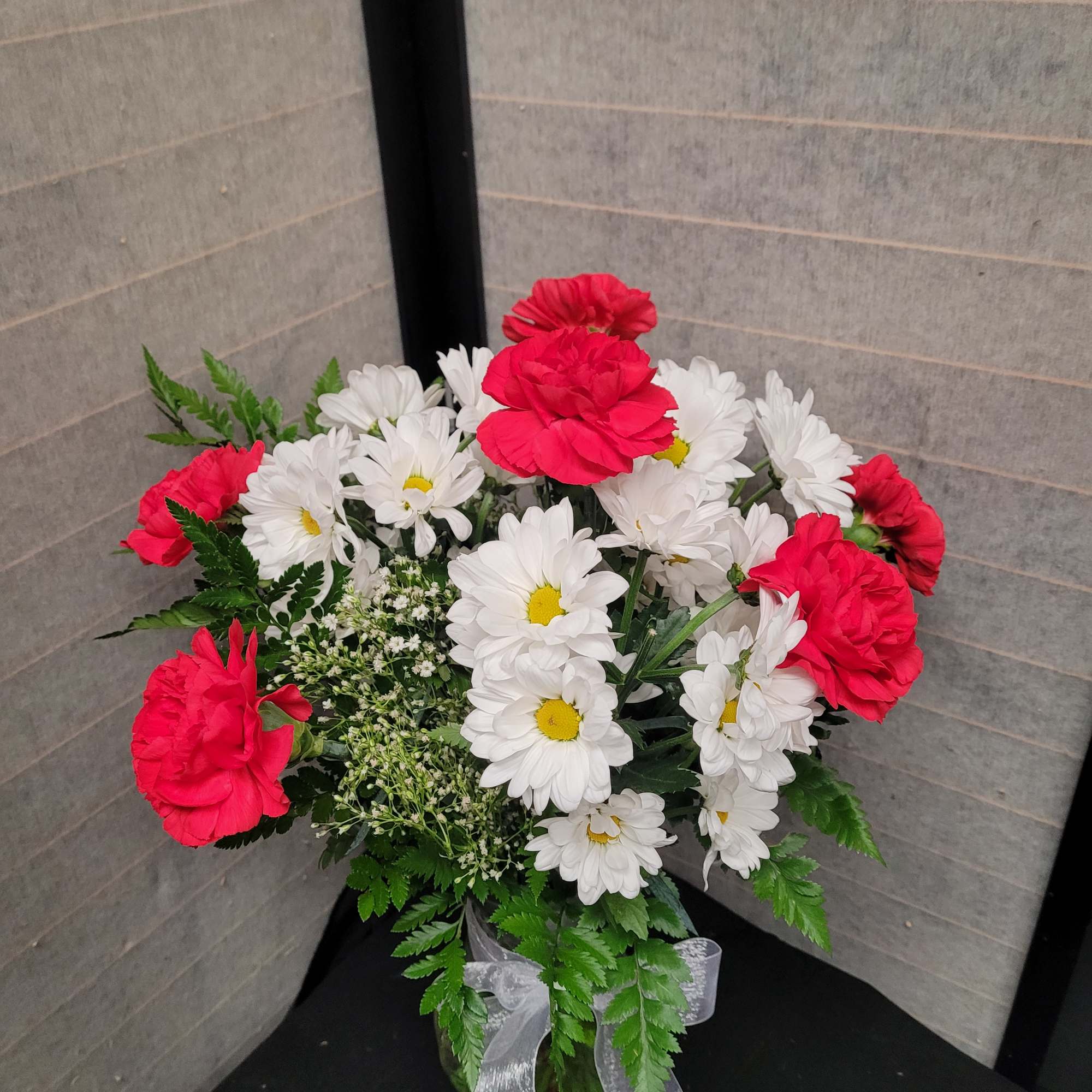 Bouquet of red carnations and white daisies in a glass vase