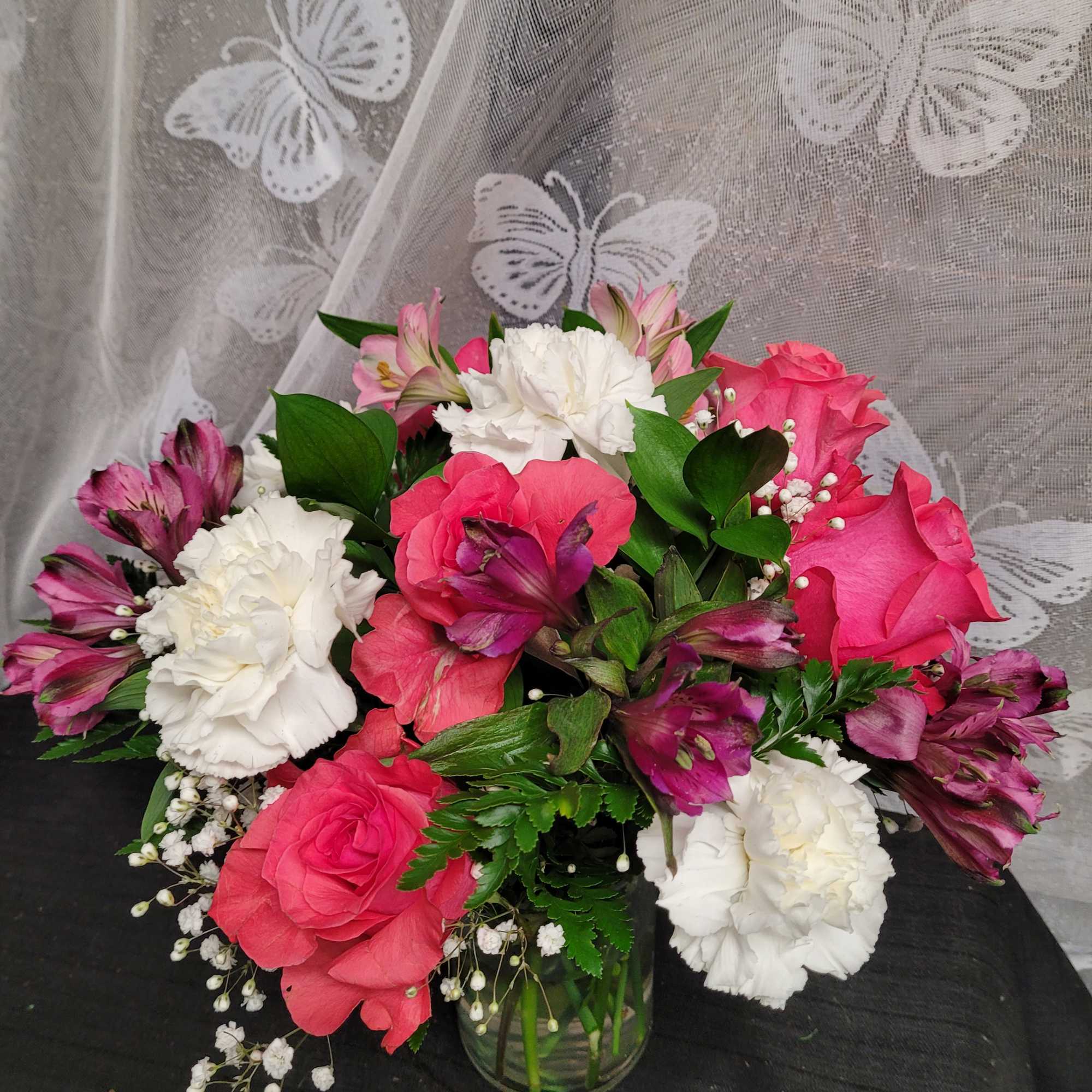 Pink roses and white carnations arranged in a glass vase