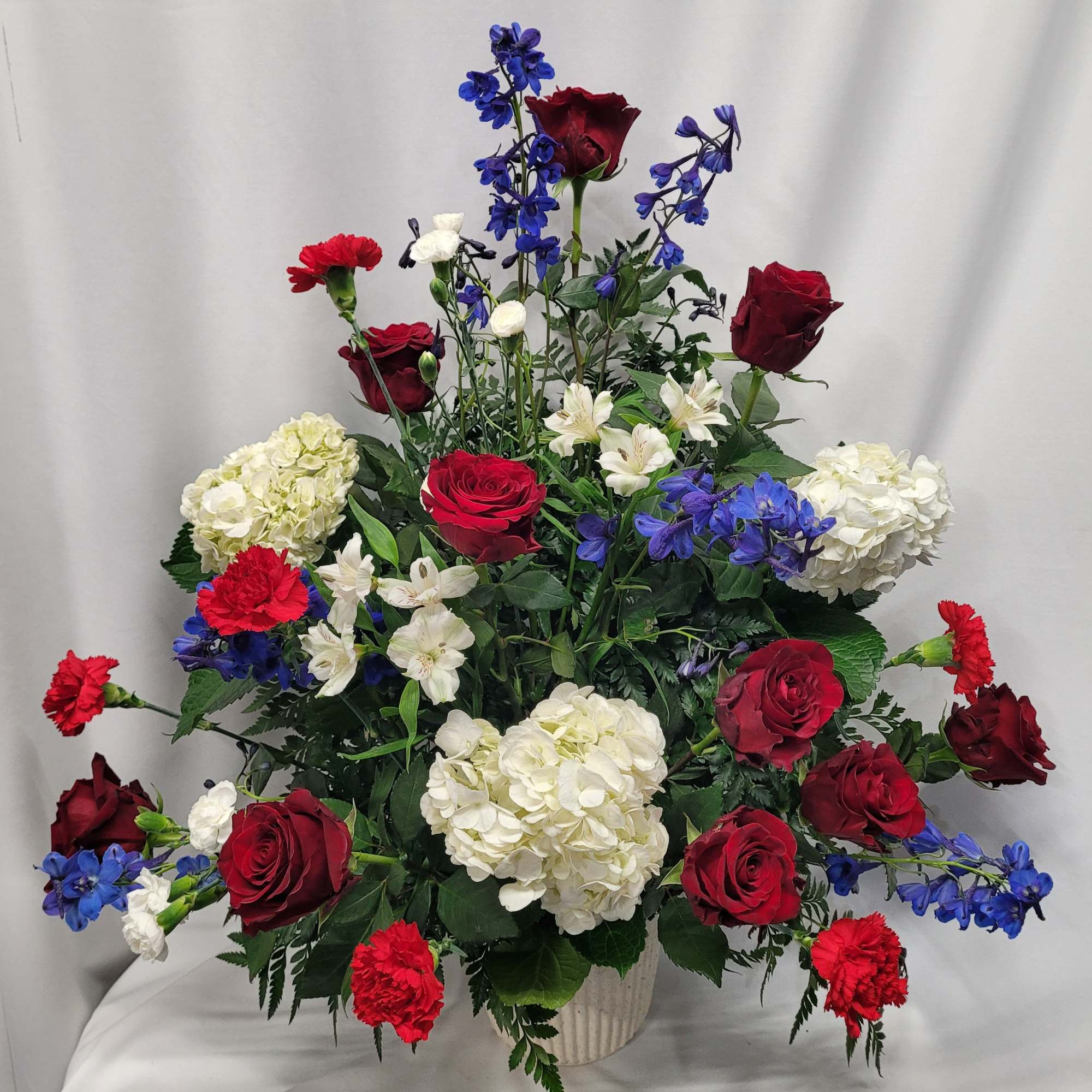 Red roses, white hydrangeas, and blue delphinium in a vase