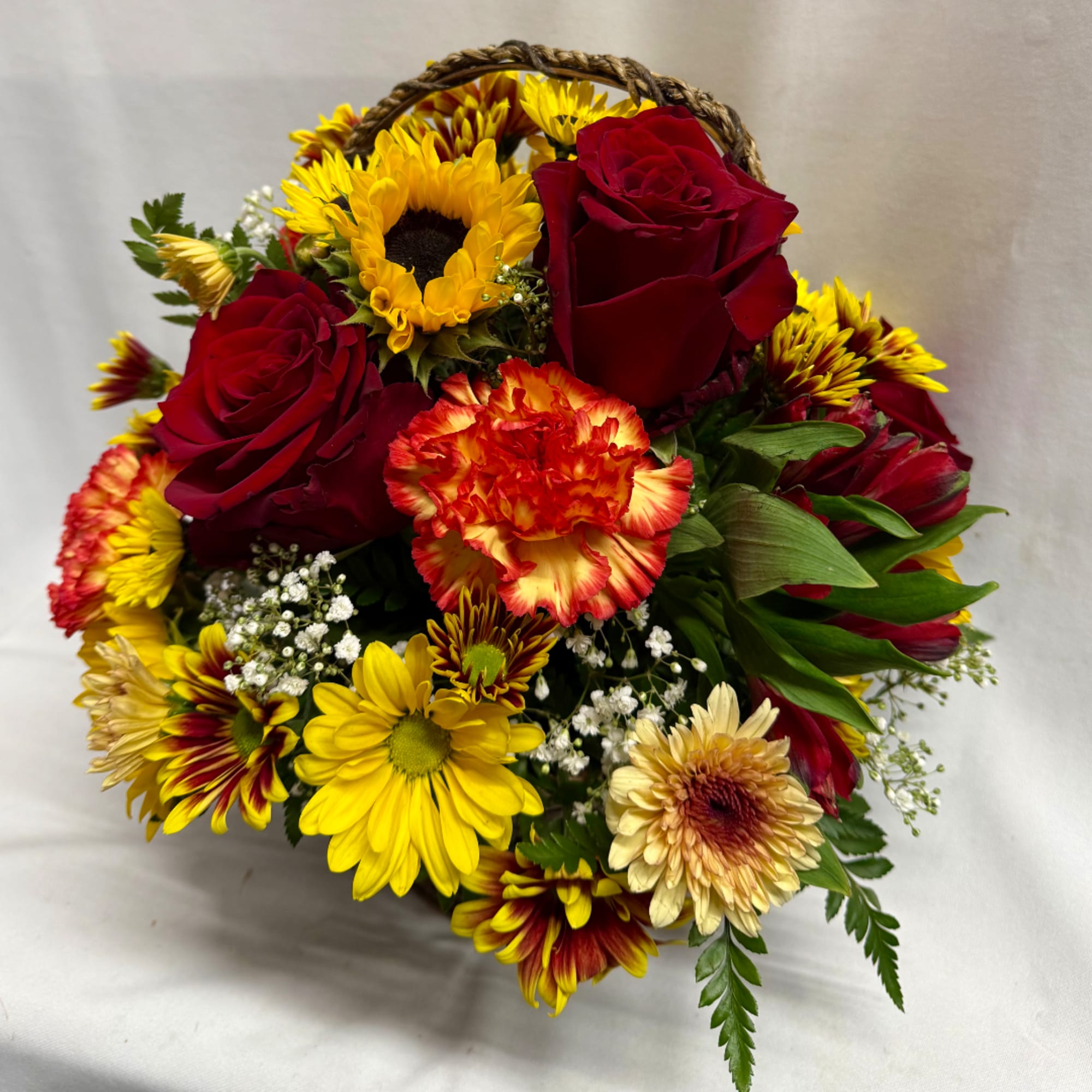 Bouquet of red roses, sunflowers, and carnations with small white filler flowers